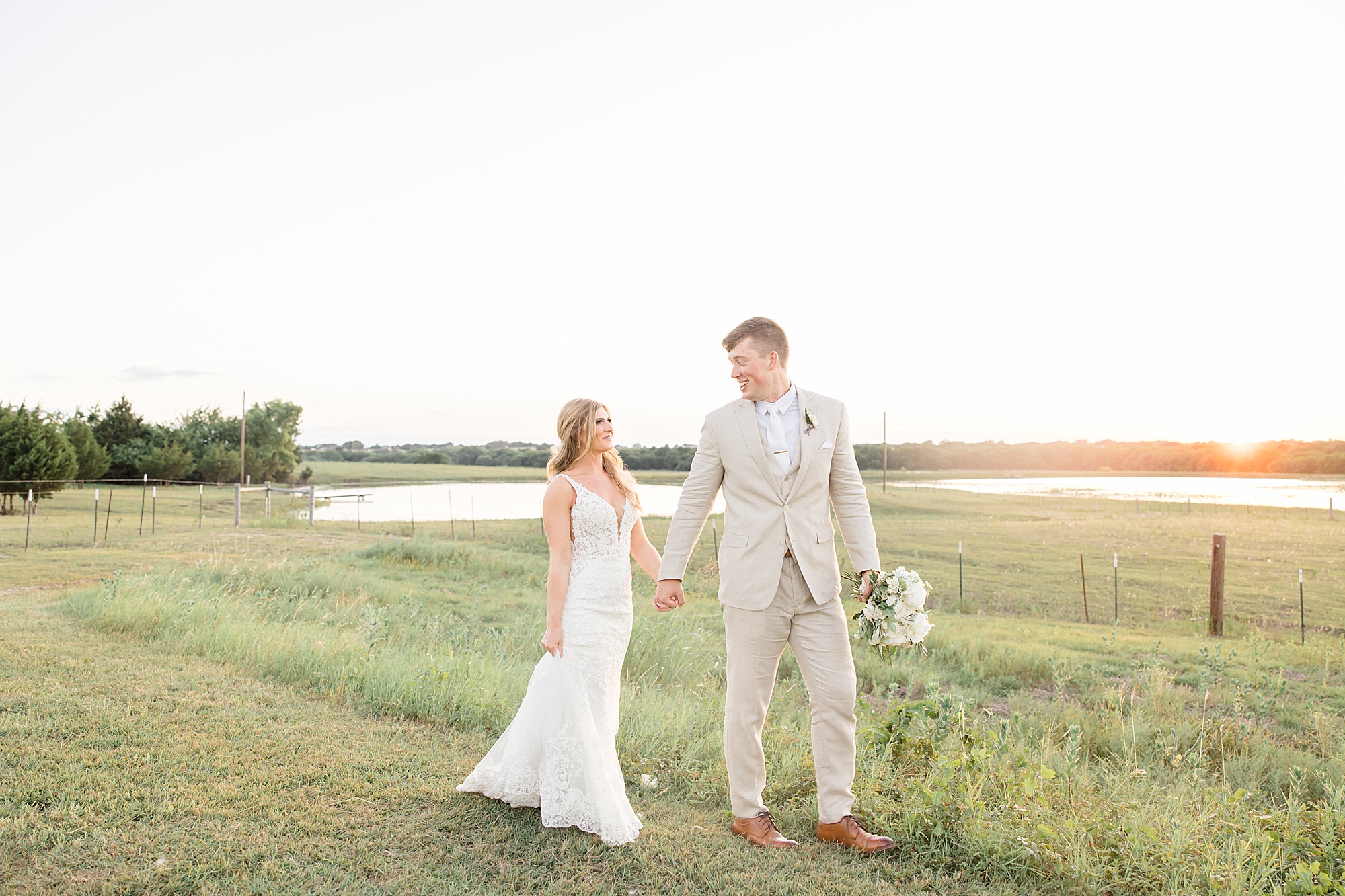 bride and groom hold hands walking through field at The Grand Ivory