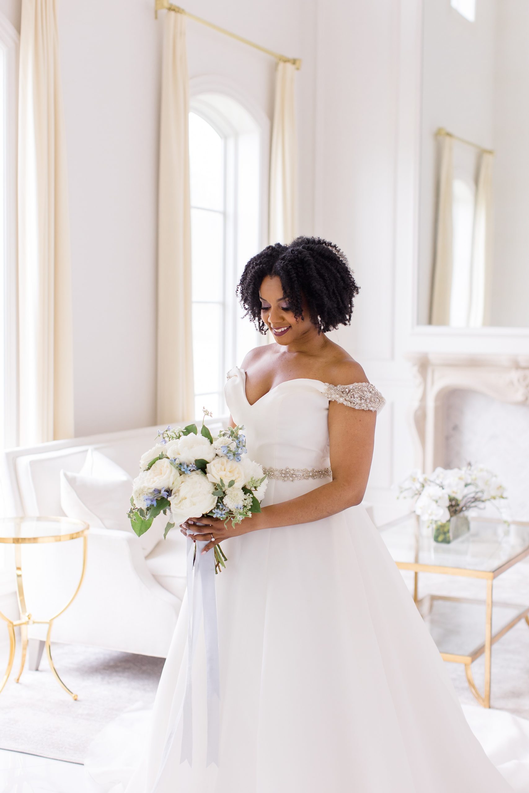 bride looks down at bouquet during portraits in bridal suite
