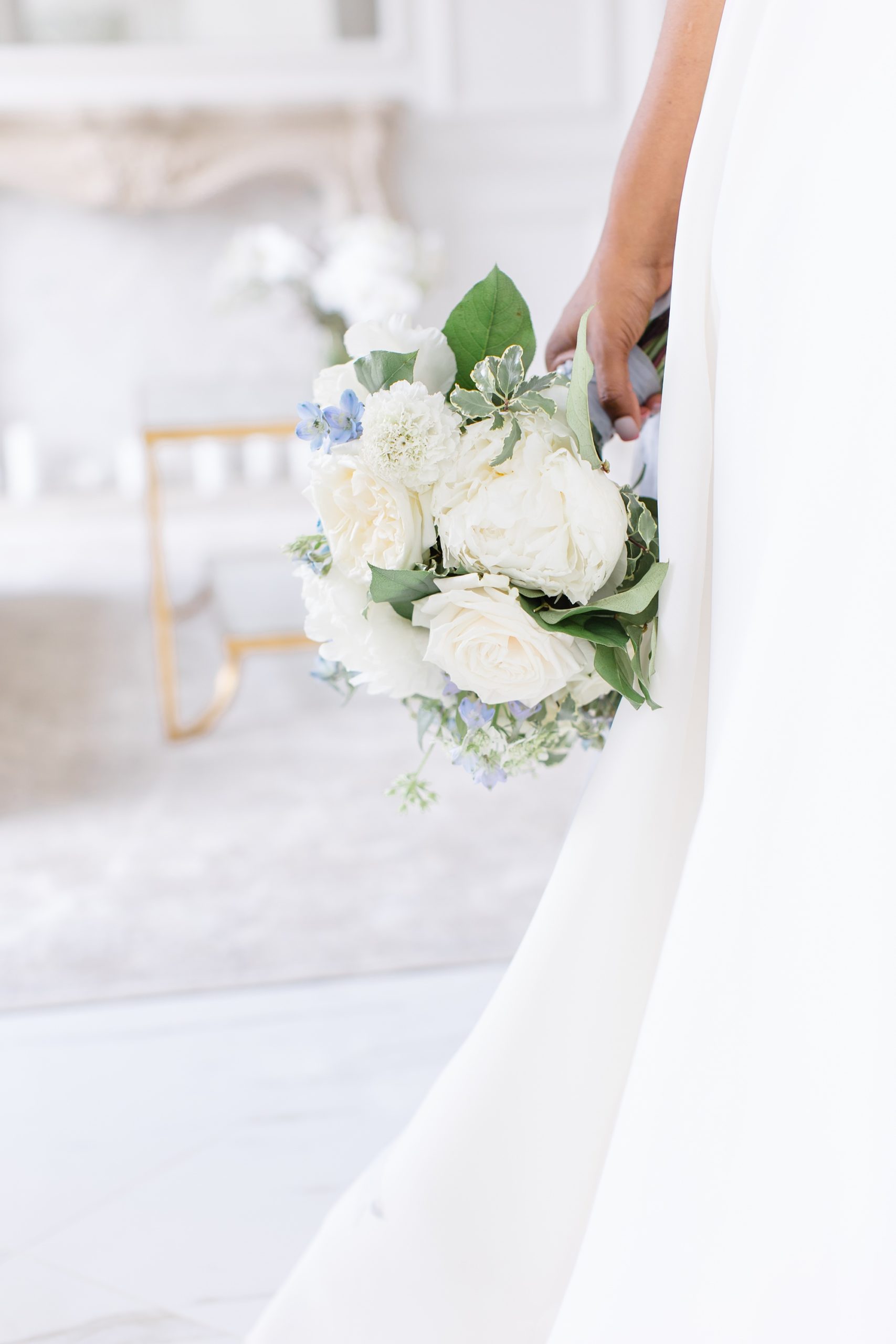 bride holds bouquet of white flowers on hip