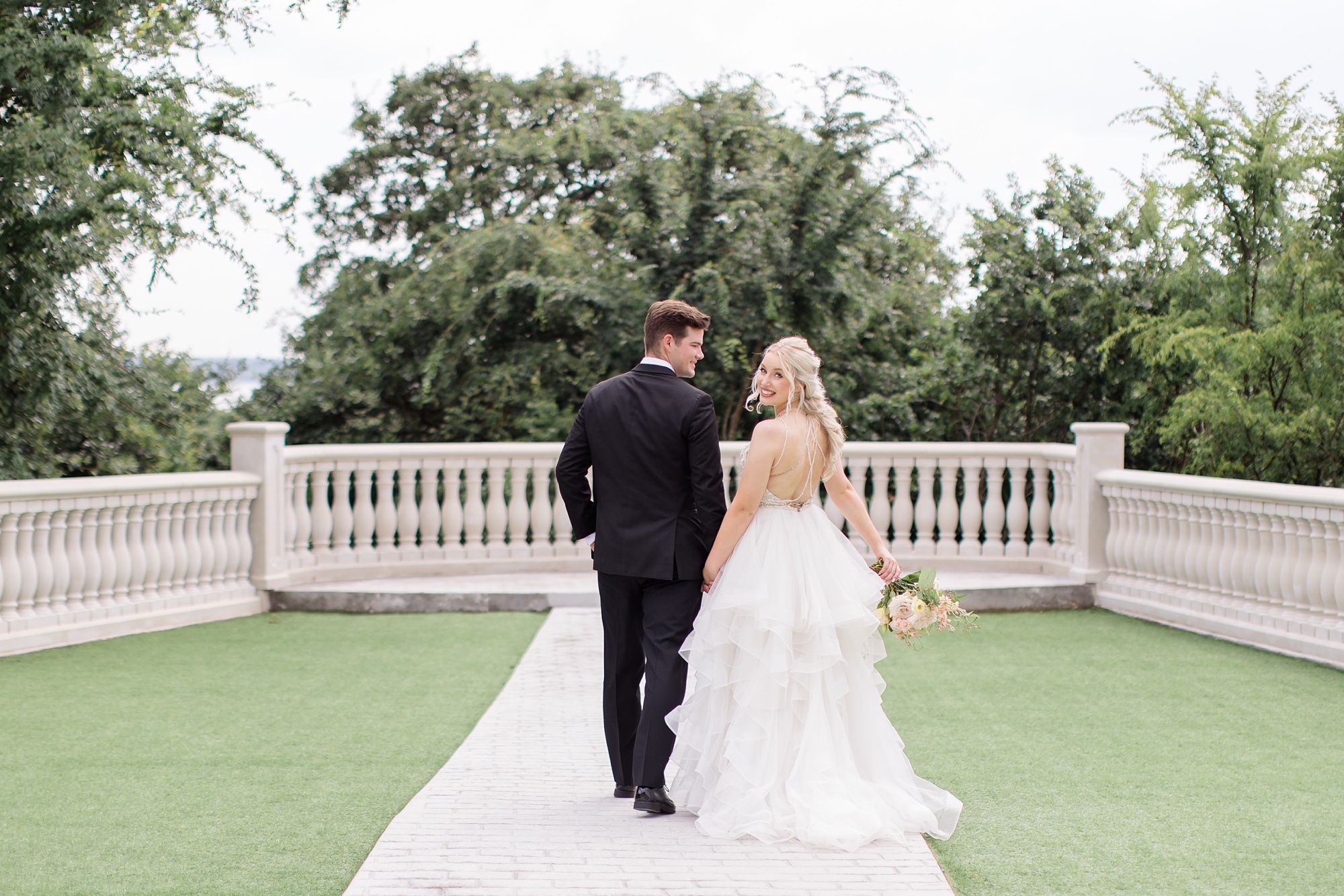 bride and groom hold hands walking towards railing at The Hillside Estate