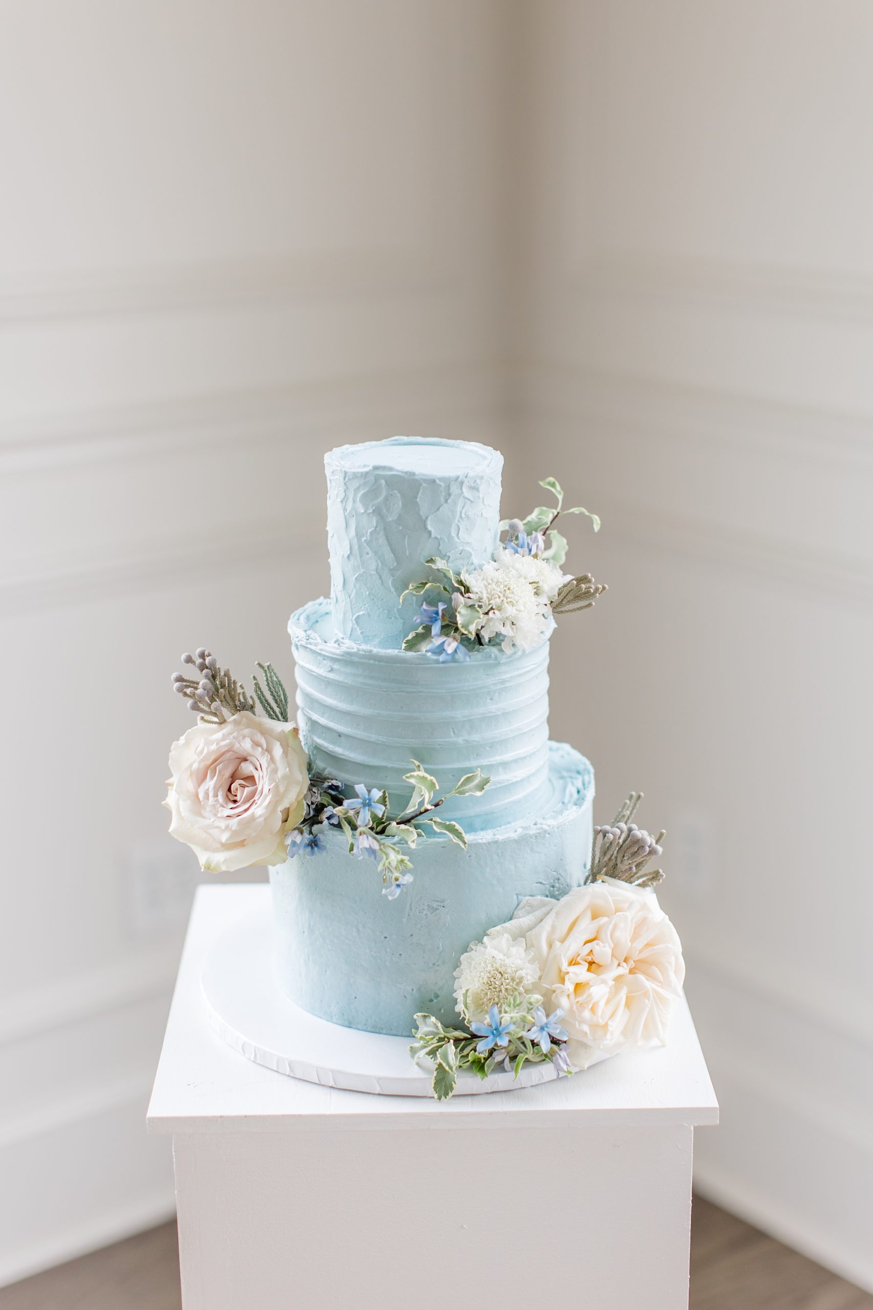 tiered wedding cake with blue icing and pink florals 