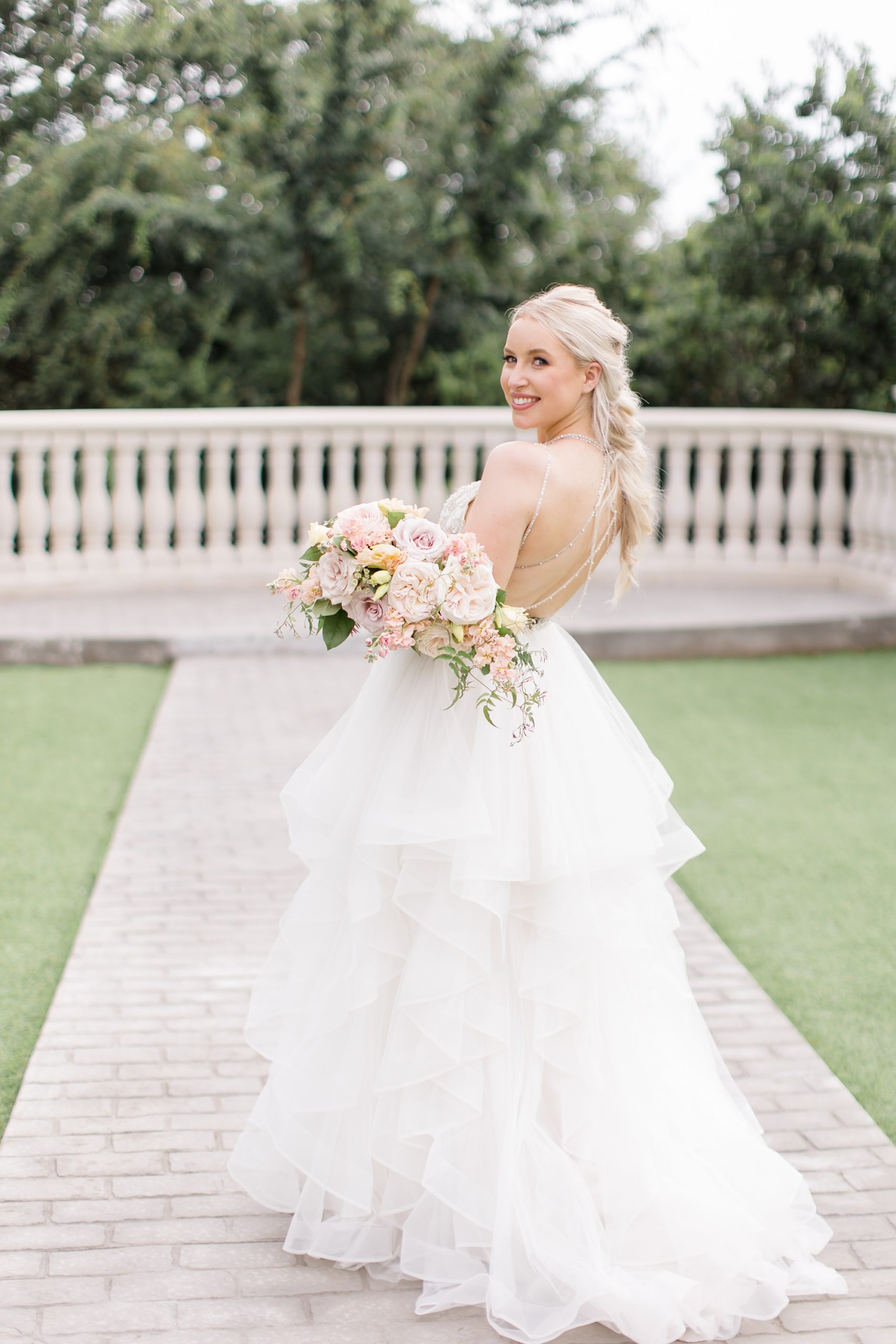 bride looks over shoulder in wedding gown holding bouquet 