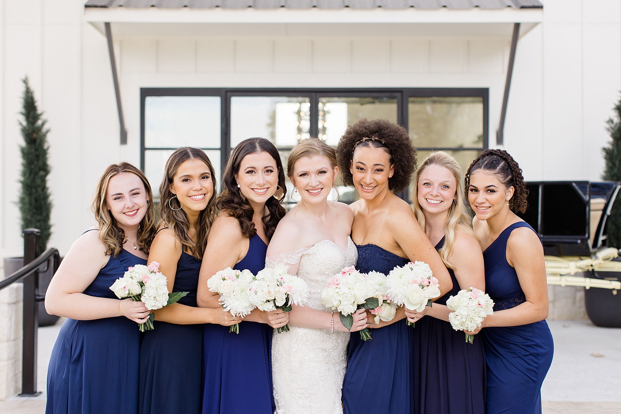 bride and bridesmaids pose with bouquets of white flowers
