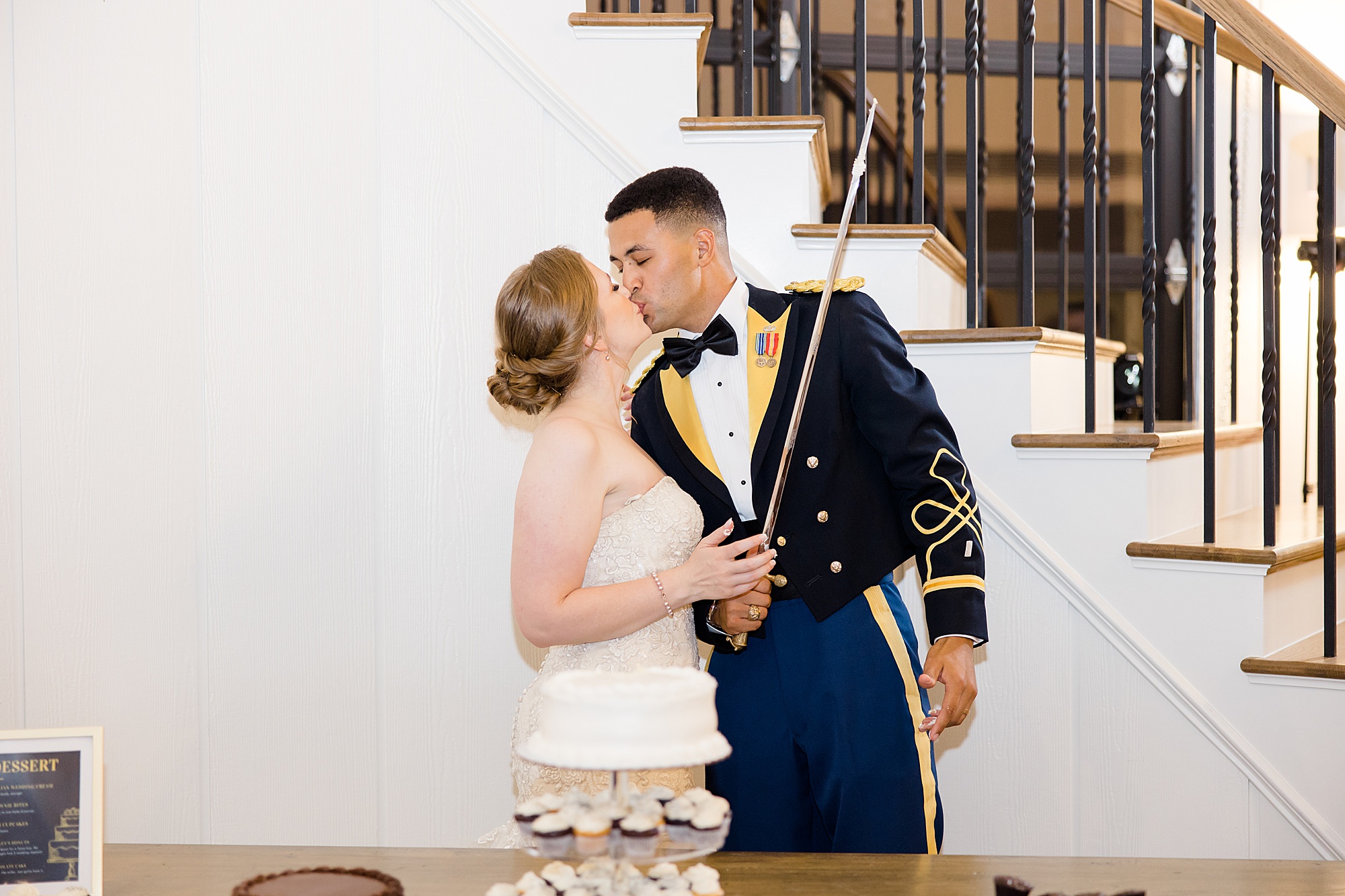 bride kisses military groom holding saber