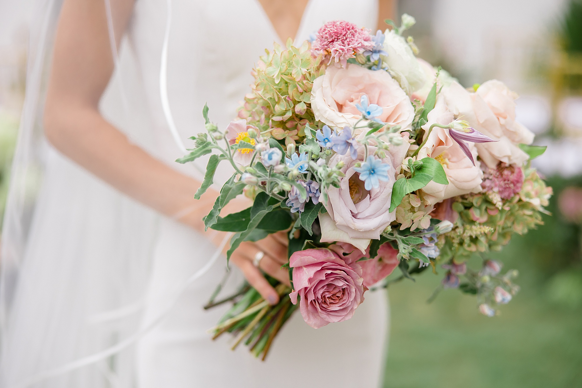 bride holds bouquet of pink and blue flowers