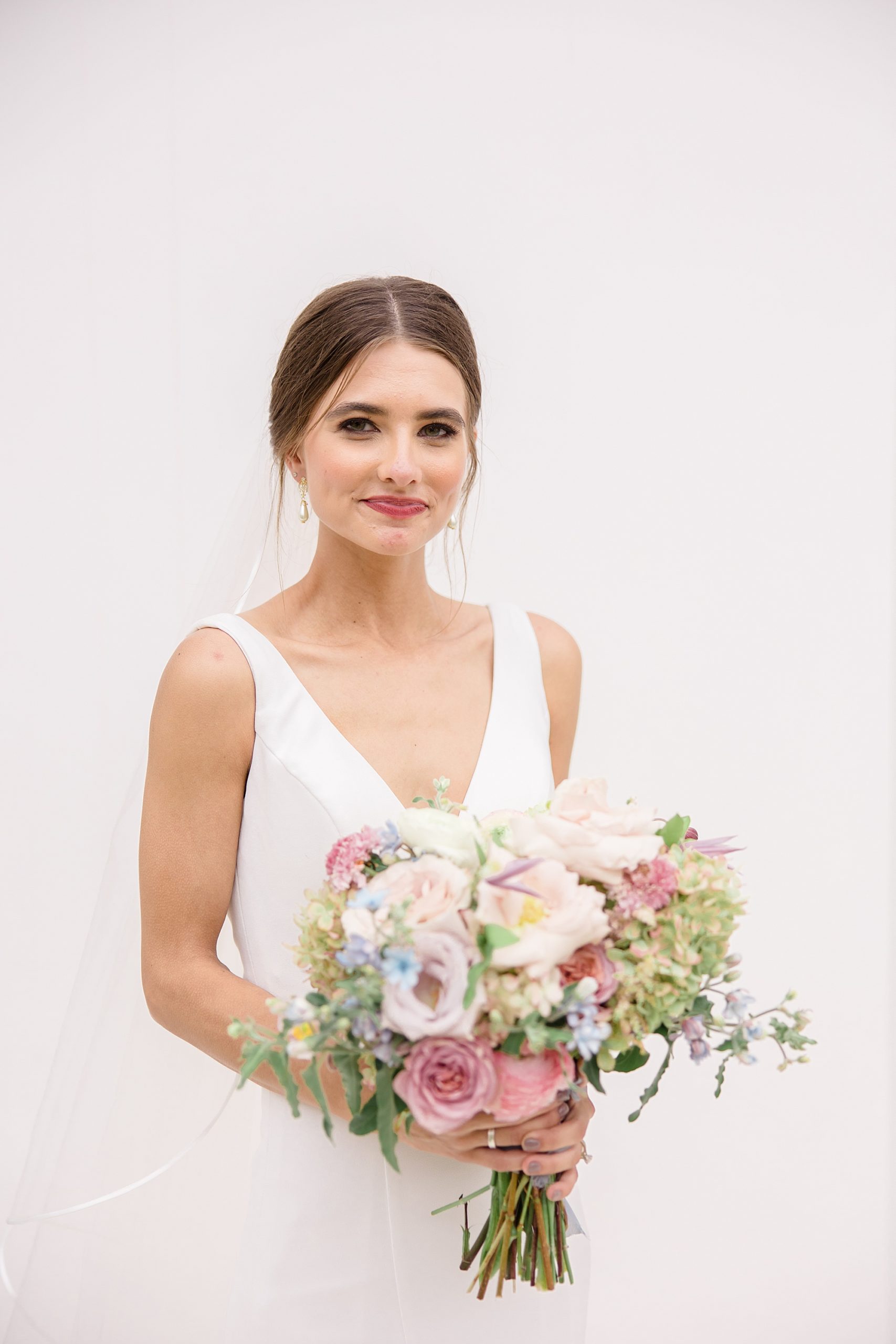 bride holds bouquet along white wall in 30A