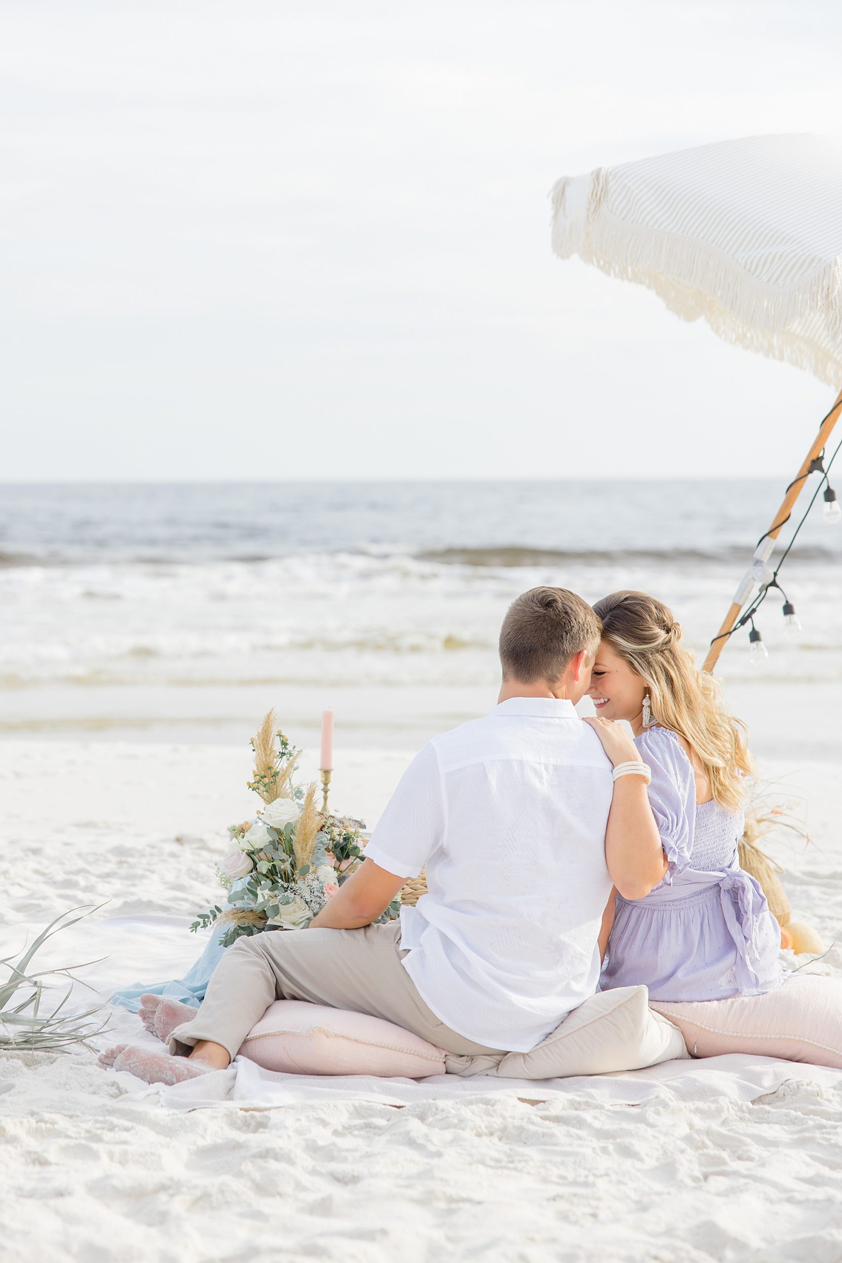 engaged couple cuddles by picnic at Rosemary Beach