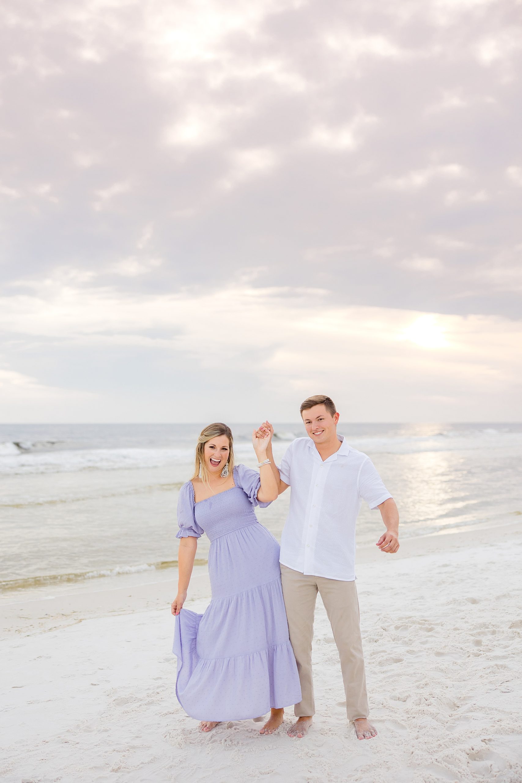 bride and groom hold hands bumping hips on beach