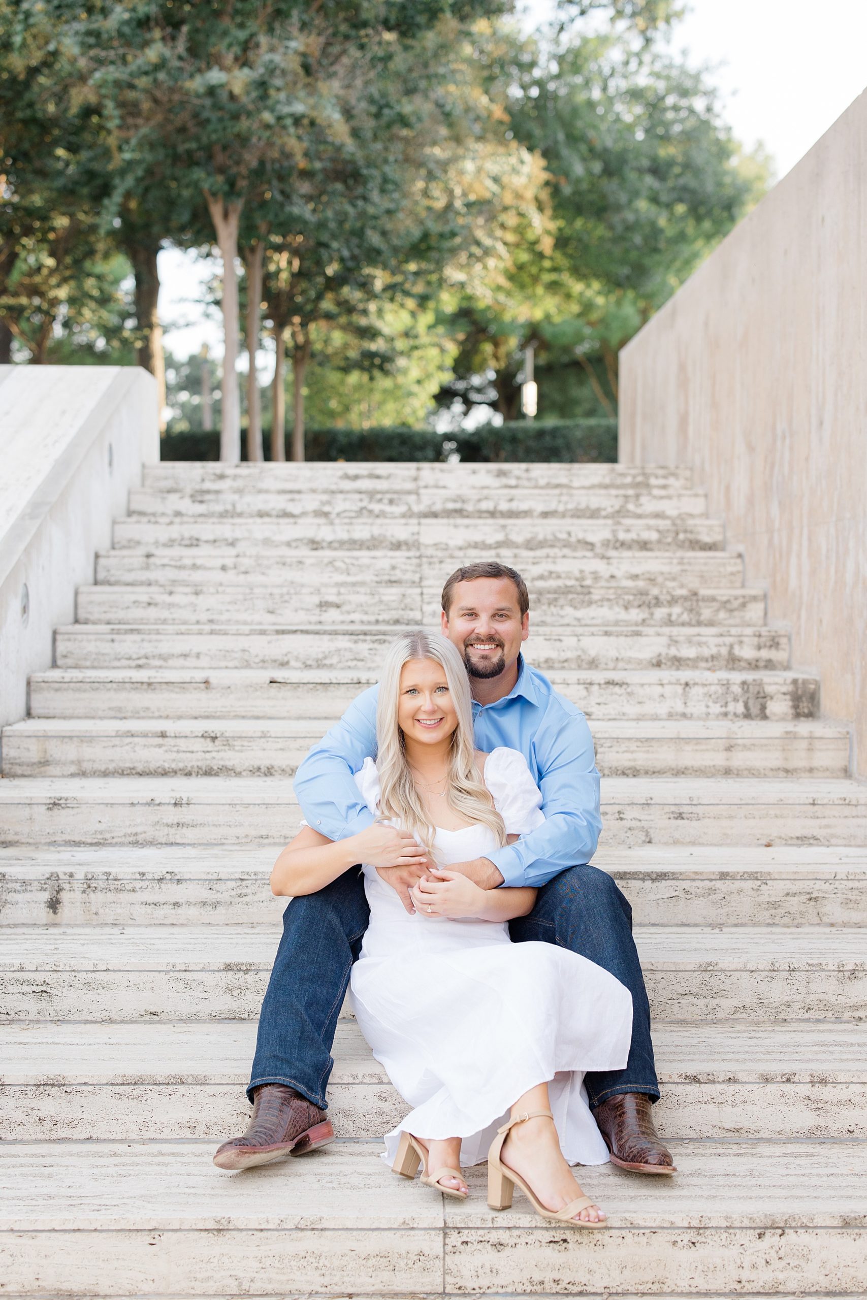 engaged couple sits on steps at the Kimball Art Museum