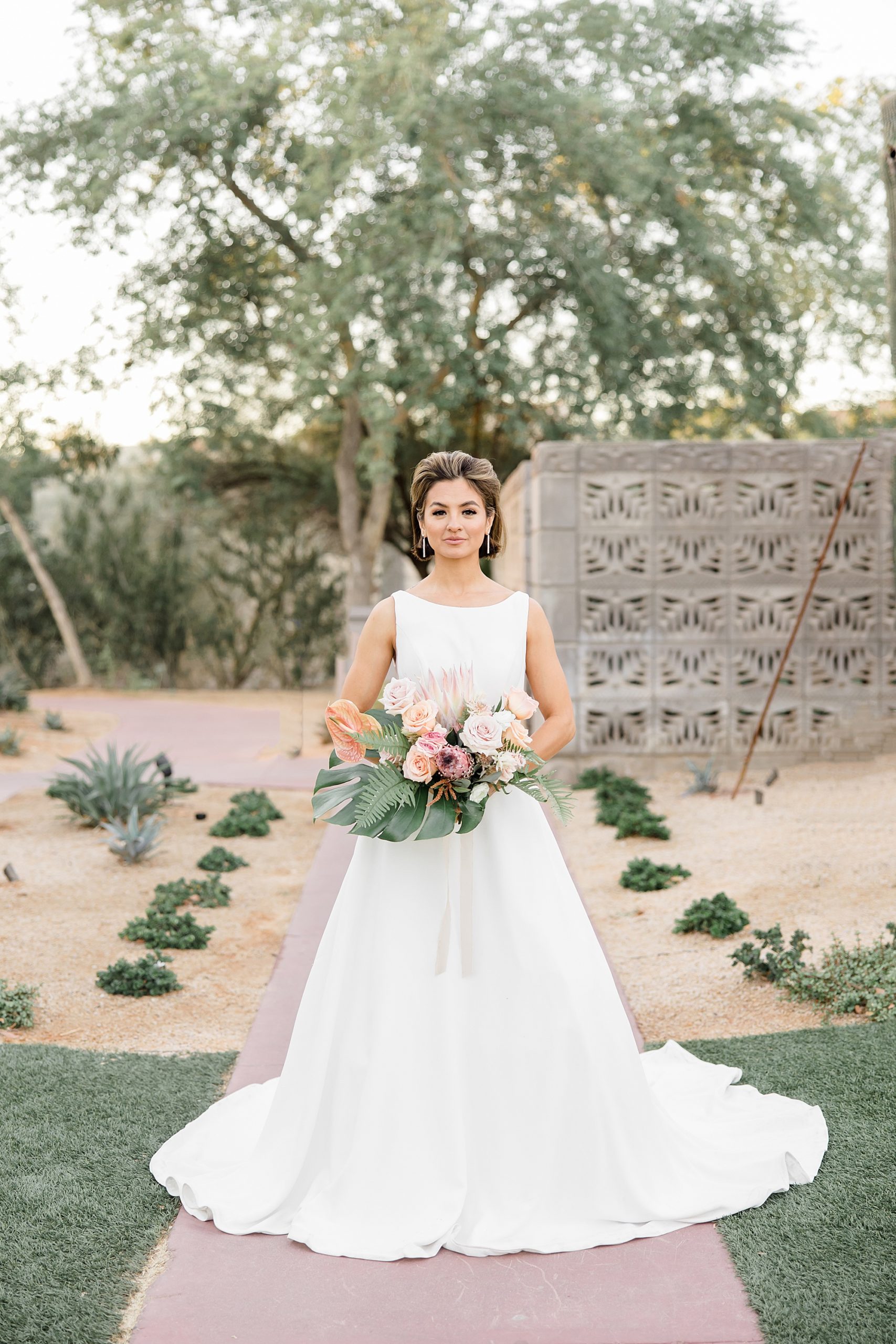 bride stands in sleek wedding gown holding bouquet 