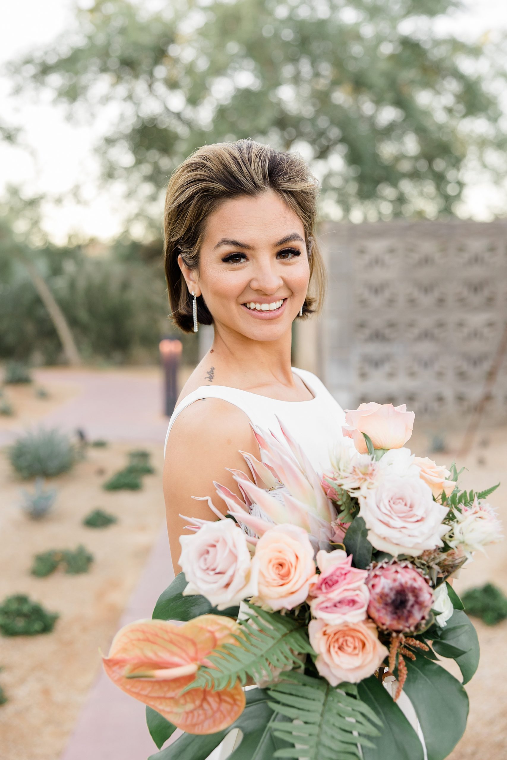 bride holds bouquet and looks over shoulder during Arizona wedding portraits 