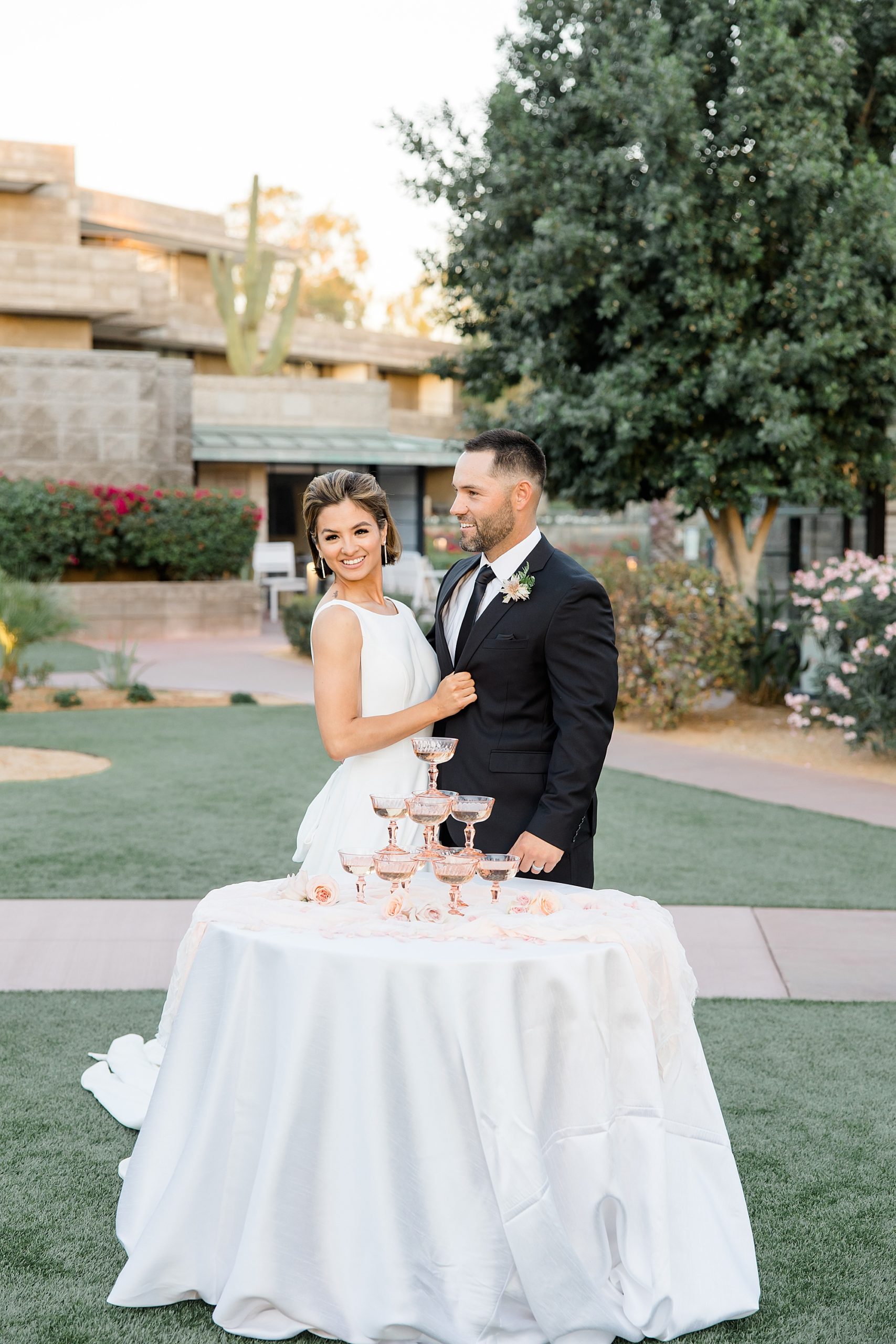 newlyweds pose behind table of vintage champagne glasses