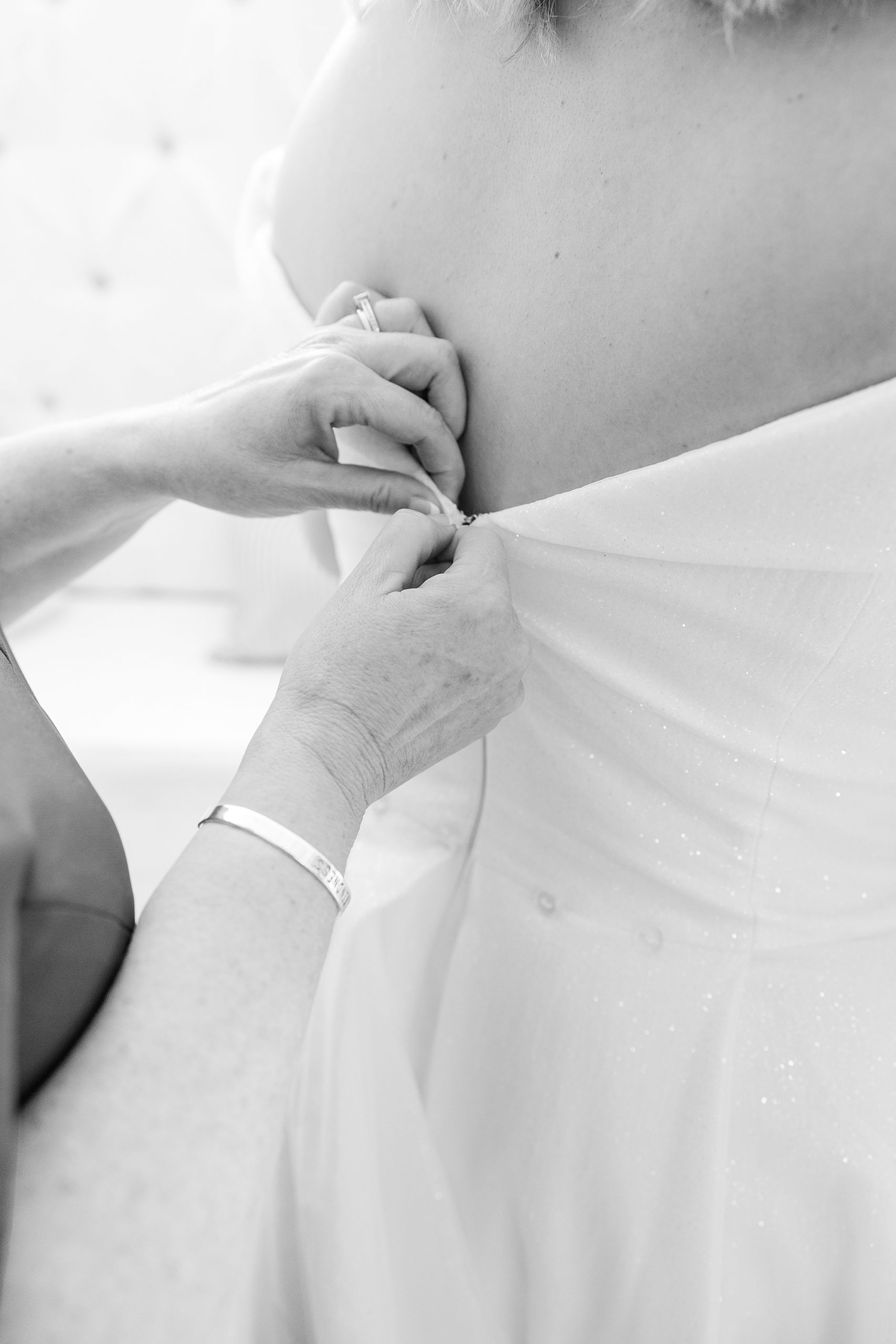 mom helps bride with wedding gown 