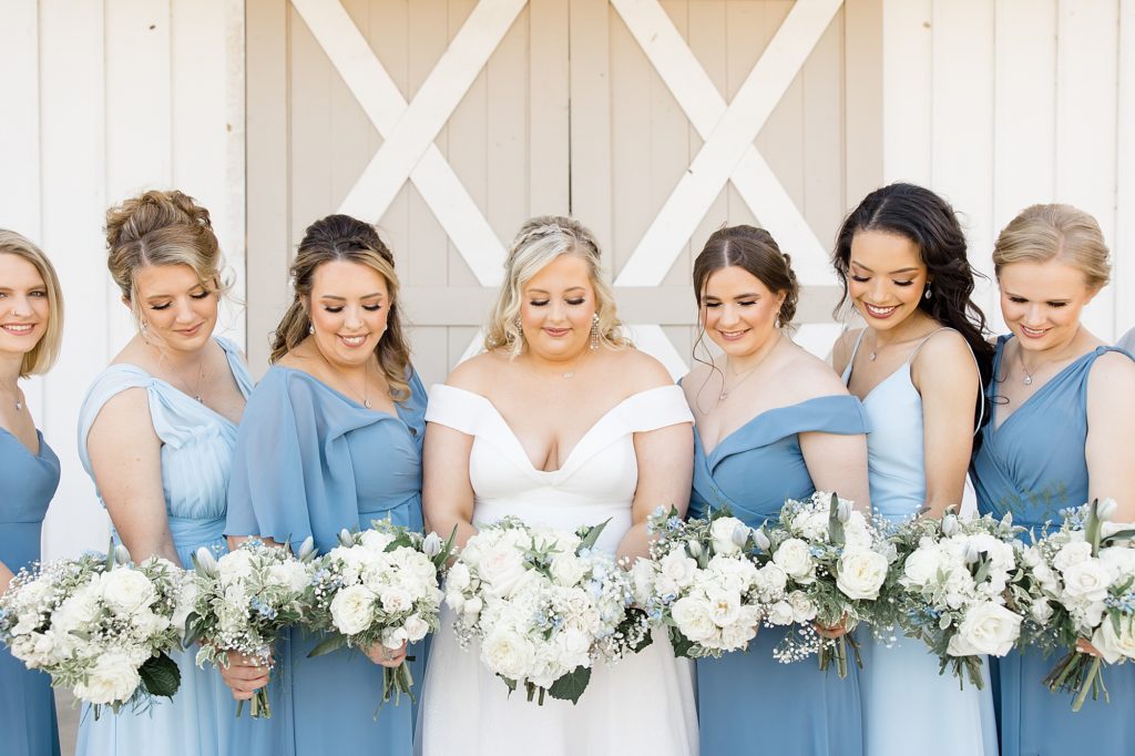 bride poses with bridesmaids in light blue gowns for fall wedding