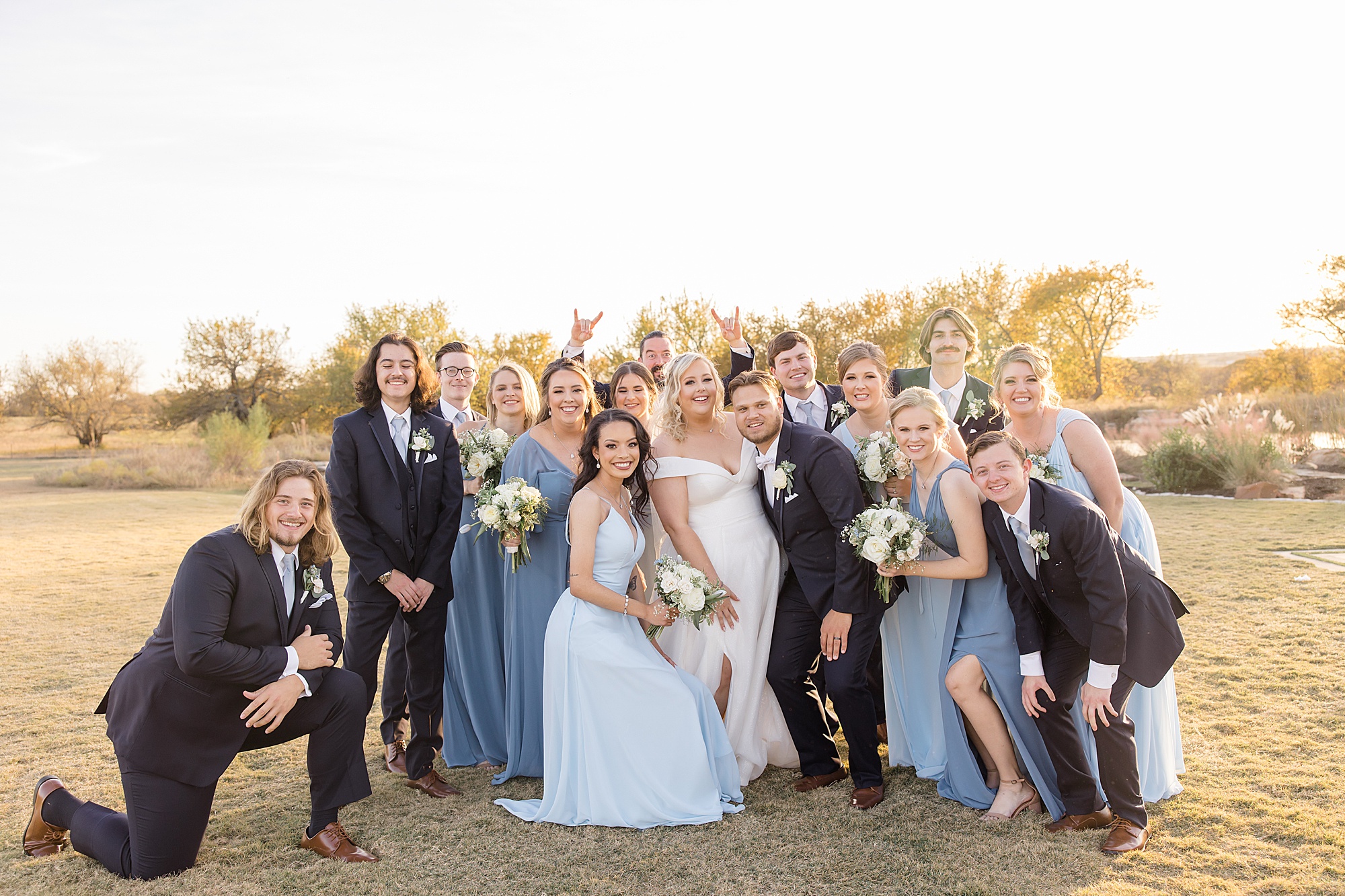 newlyweds pose with wedding party in light blue gowns and suits