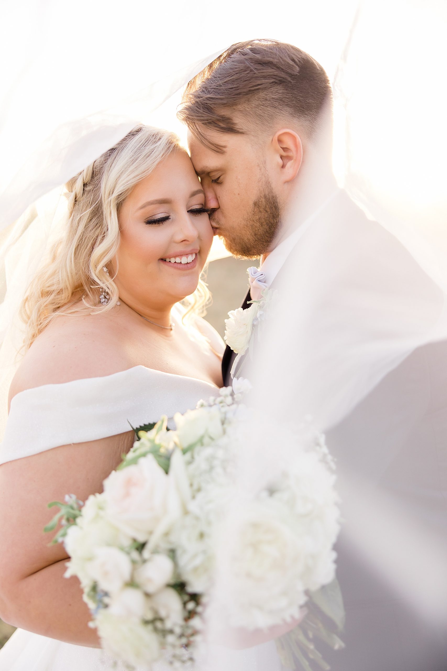 groom kisses bride's cheek during TX wedding portraits 