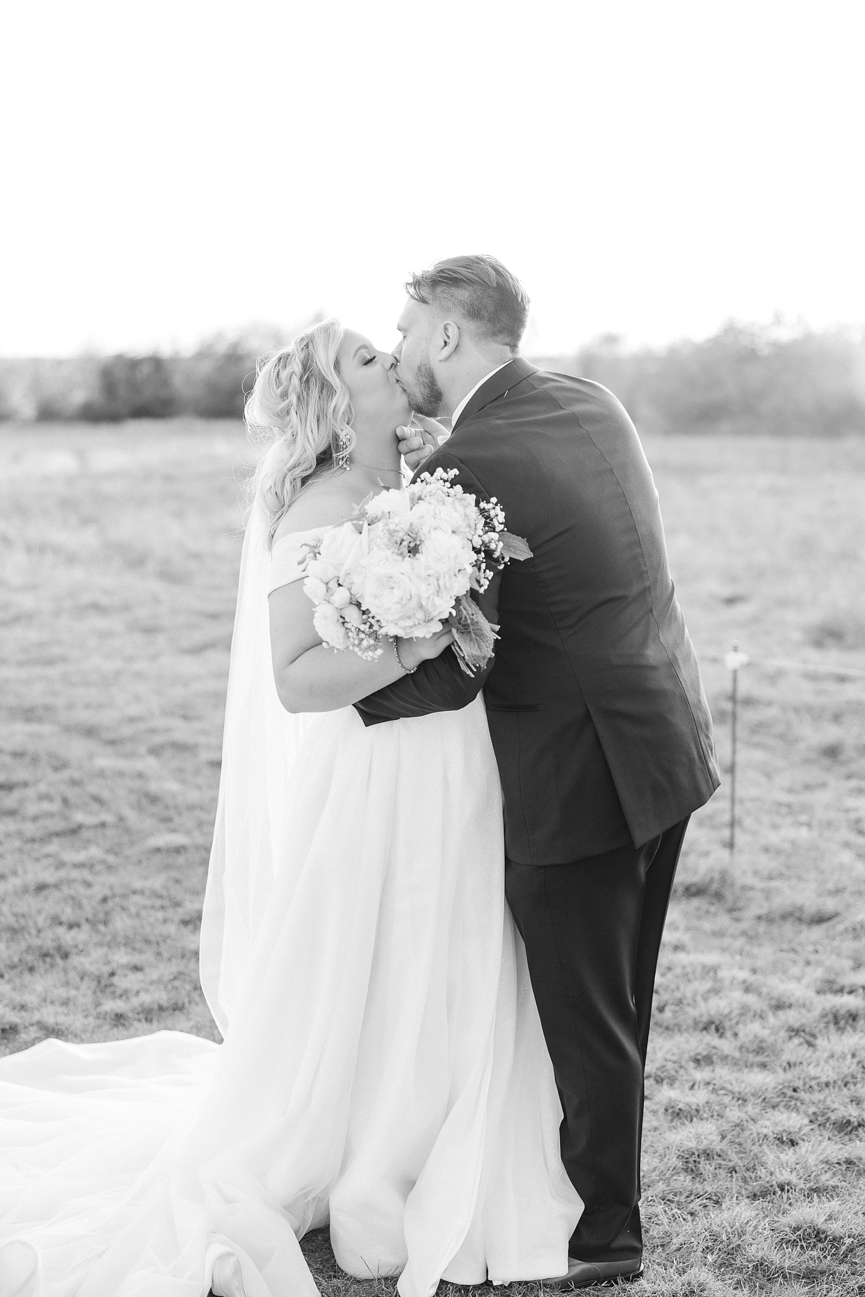 newlyweds kiss in field at the Nest at Ruth Farms