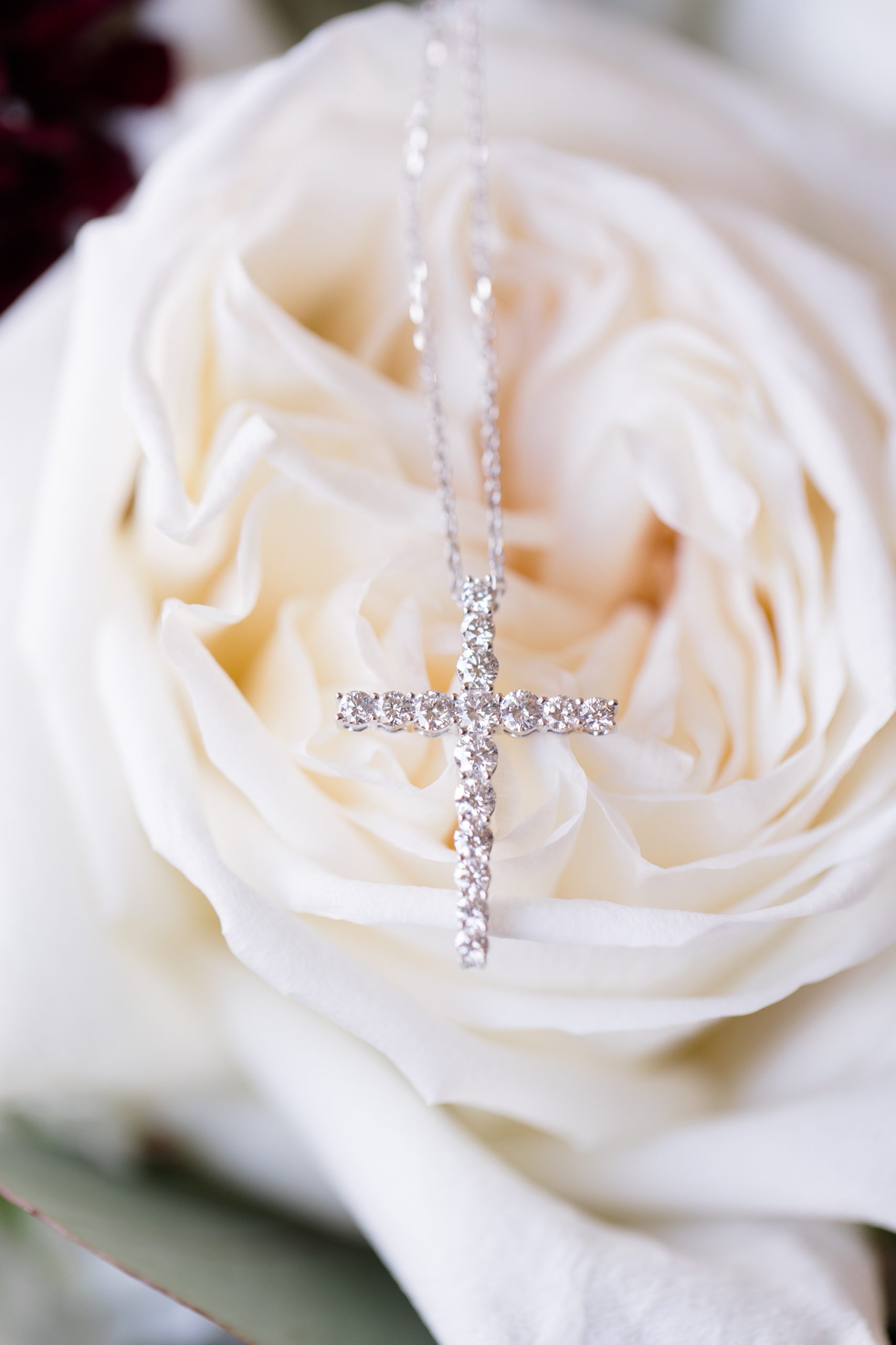 bride's cross necklace rests on ivory rose