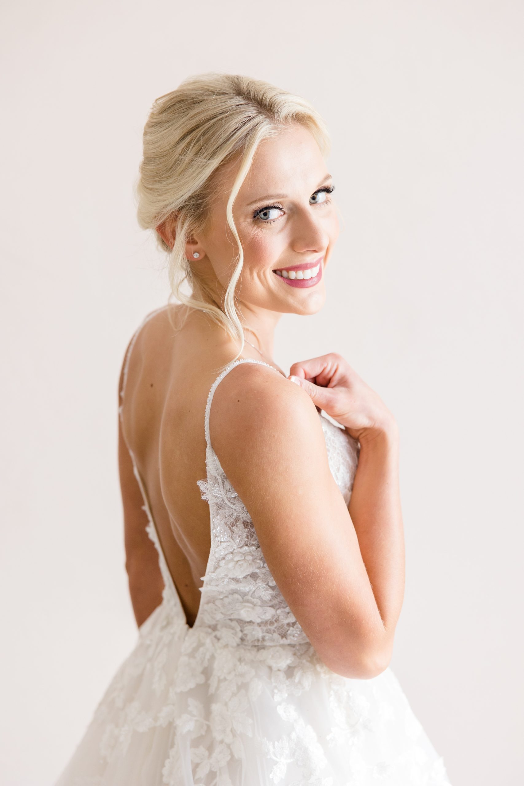 bride looks over shoulder holding the strap of wedding gown