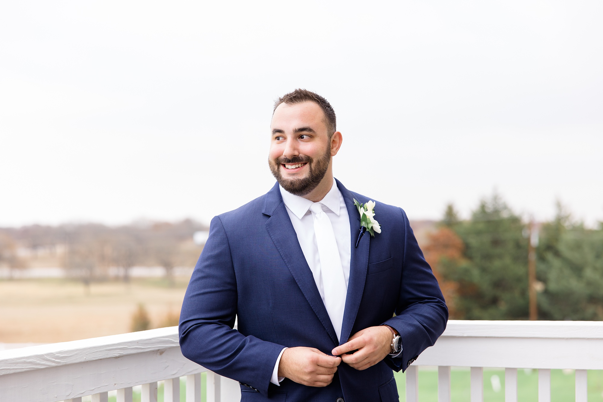 groom buttons suit jacket during Texas wedding prep