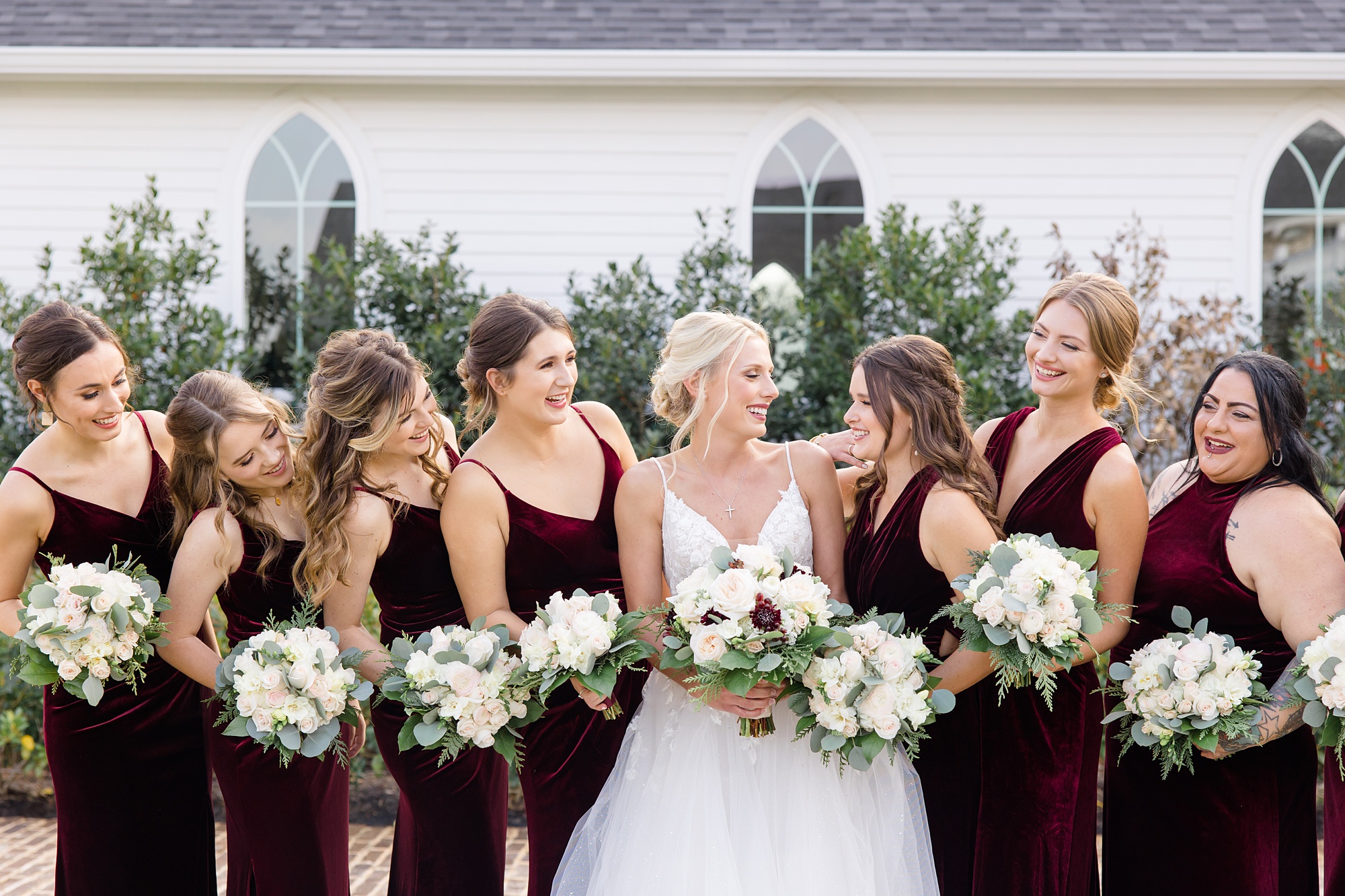bride looks at bridesmaids in burgundy gowns for winter wedding