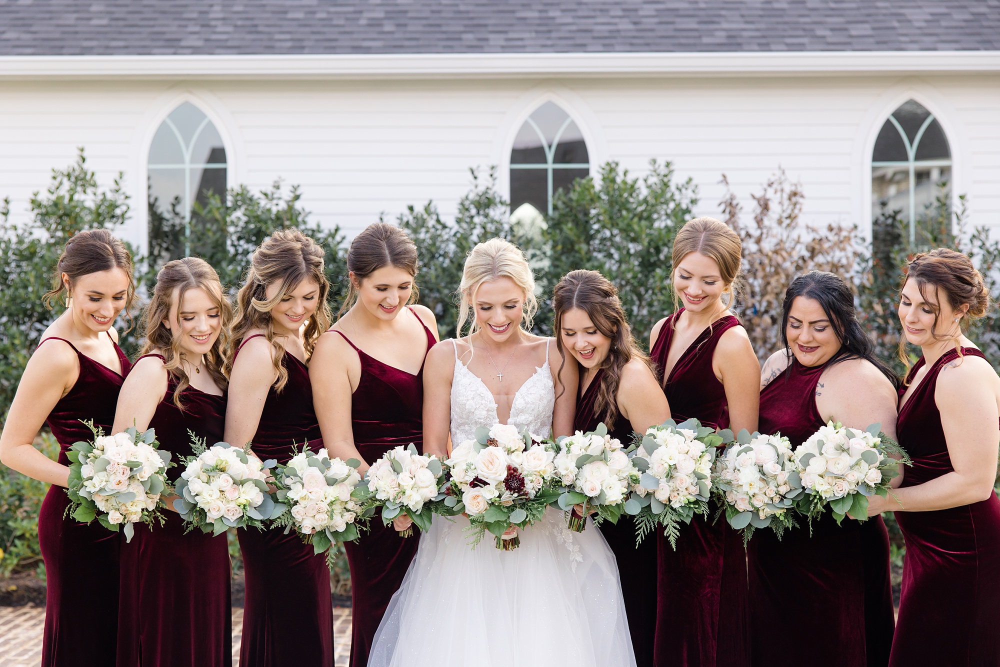 bride and bridesmaids hold white and red bouquets before winter wedding