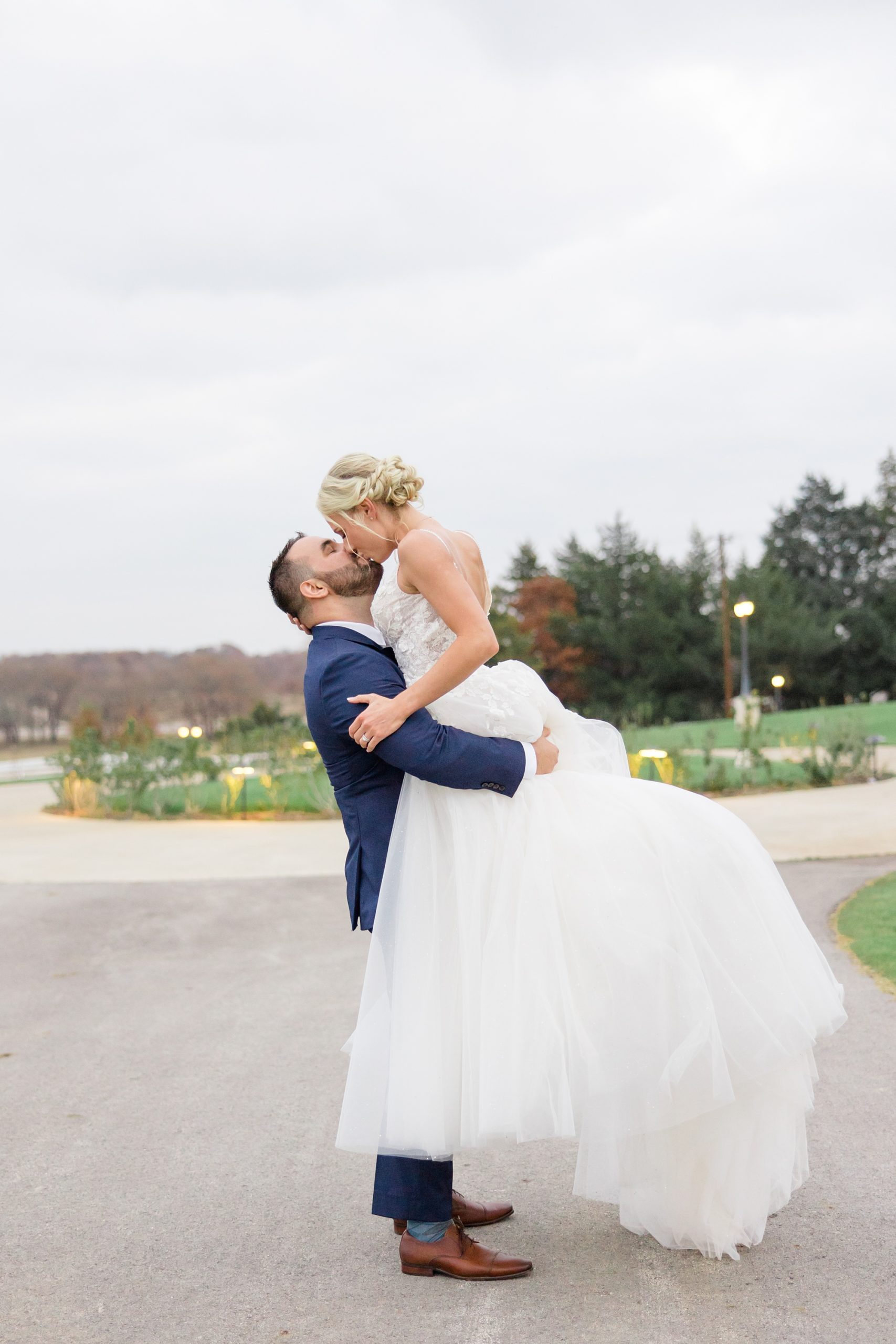 groom lifts bride during wedding photos in Texas