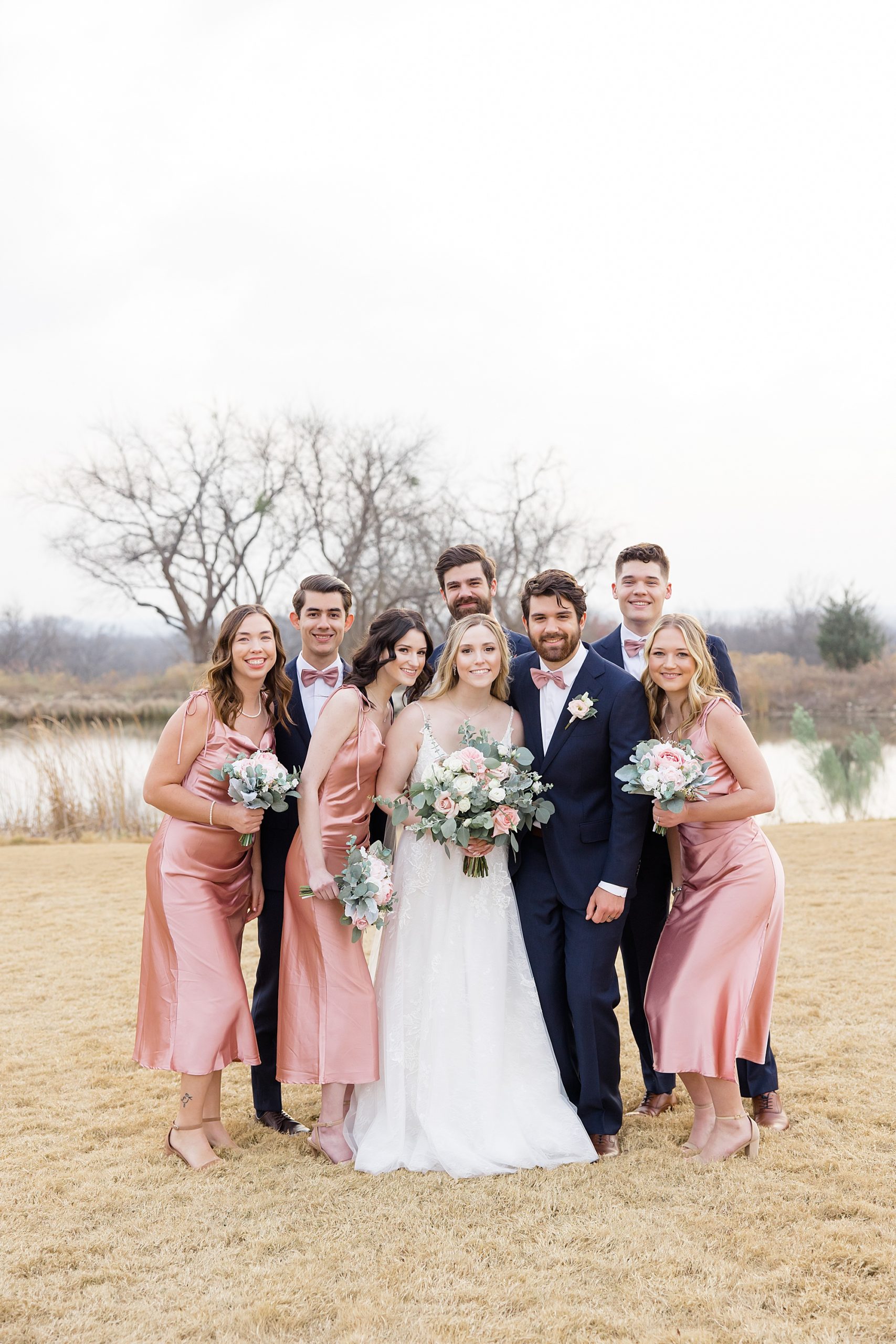 newlyweds pose with wedding party in pink and blue