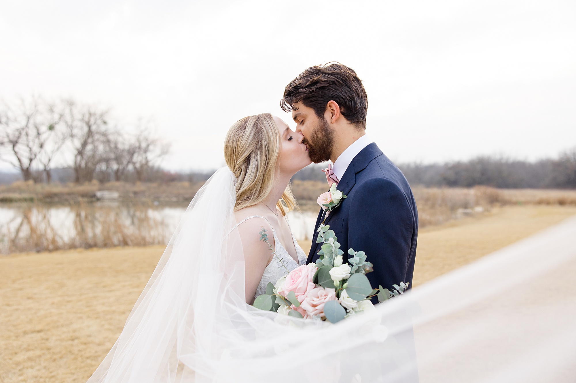 newlyweds kiss while bride's veil wraps around them