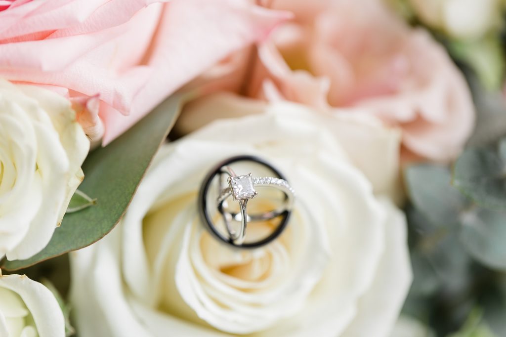wedding rings lay on ivory rose before TX wedding