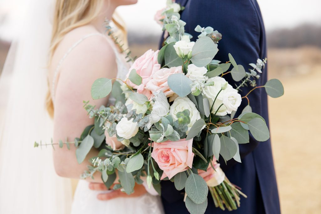 bride holds bouquet of pink and ivory flowers 
