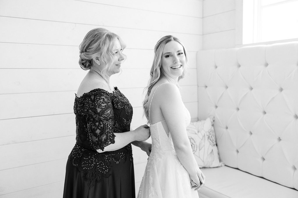 mother helps bride with wedding gown before The Nest at Ruth Farms winter wedding