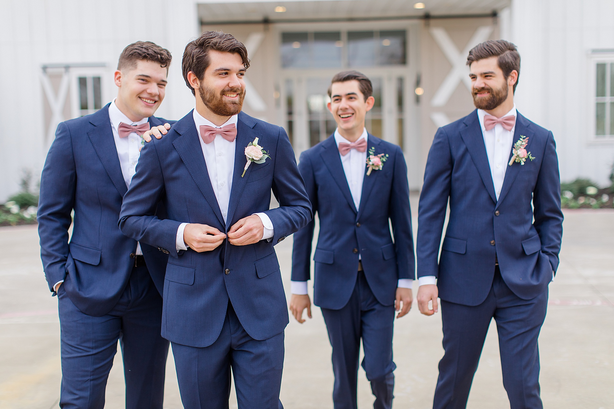 groom walks with groomsmen in navy suits before wedding in Texas
