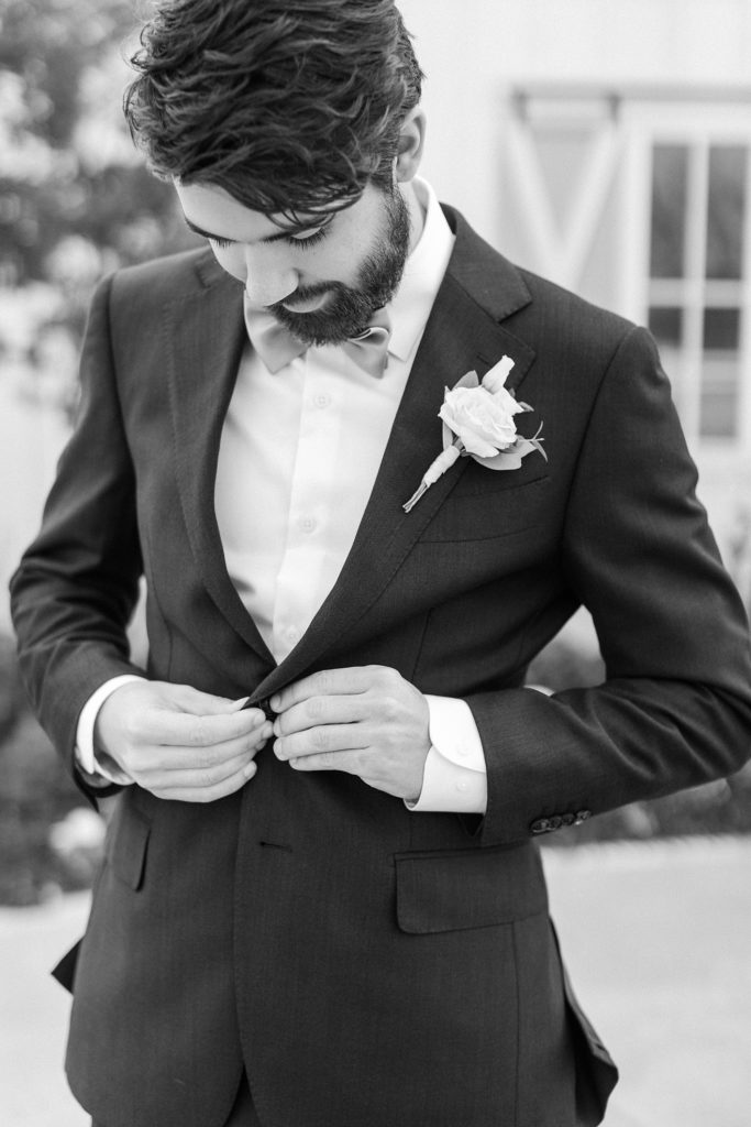 groom buttons suit jacket before wedding in Dallas TX