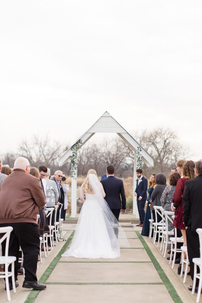 bride walks down aisle for outdoor wedding ceremony in the winter