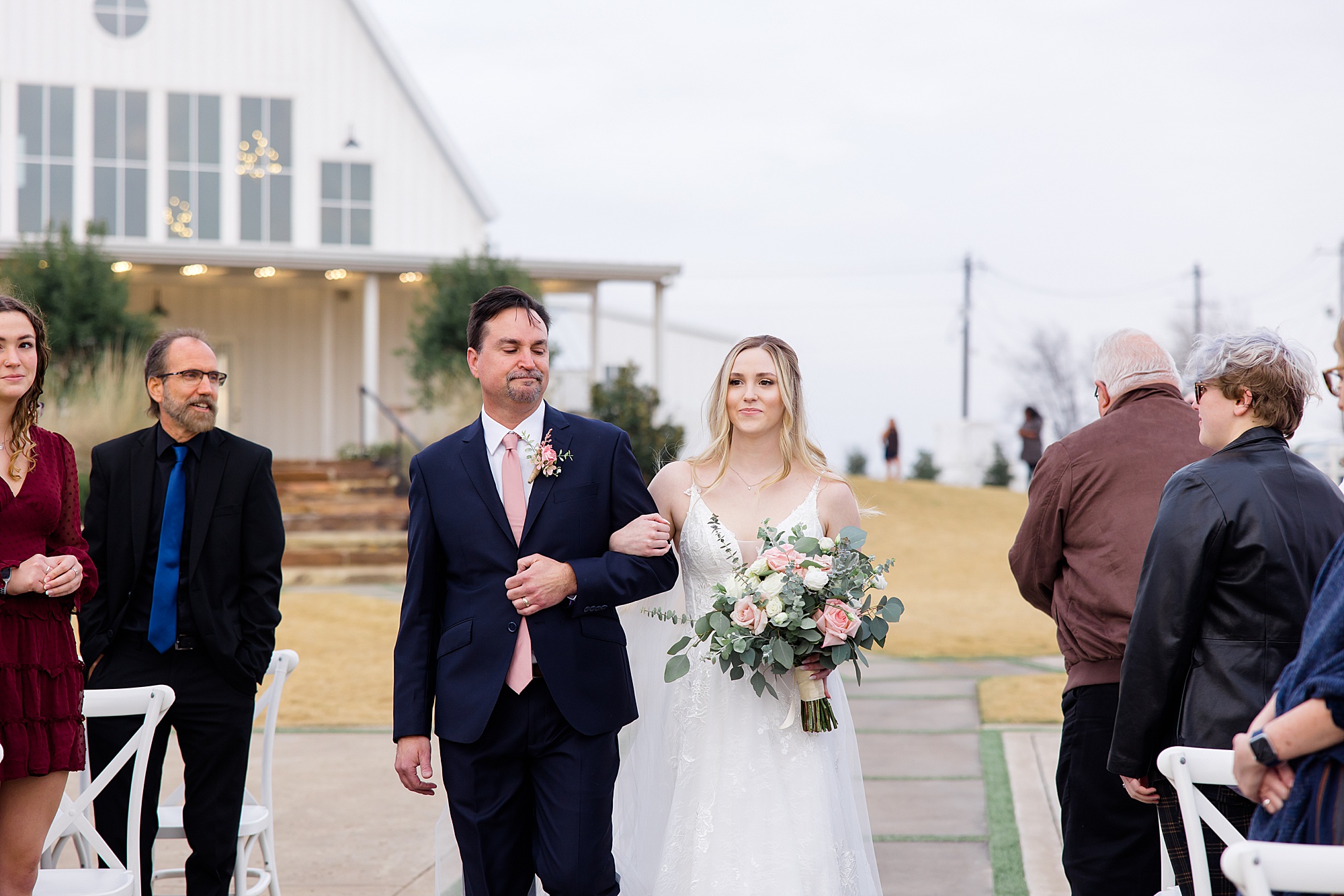 bride walks down the aisle with dad for outdoor wedding ceremony in the winter