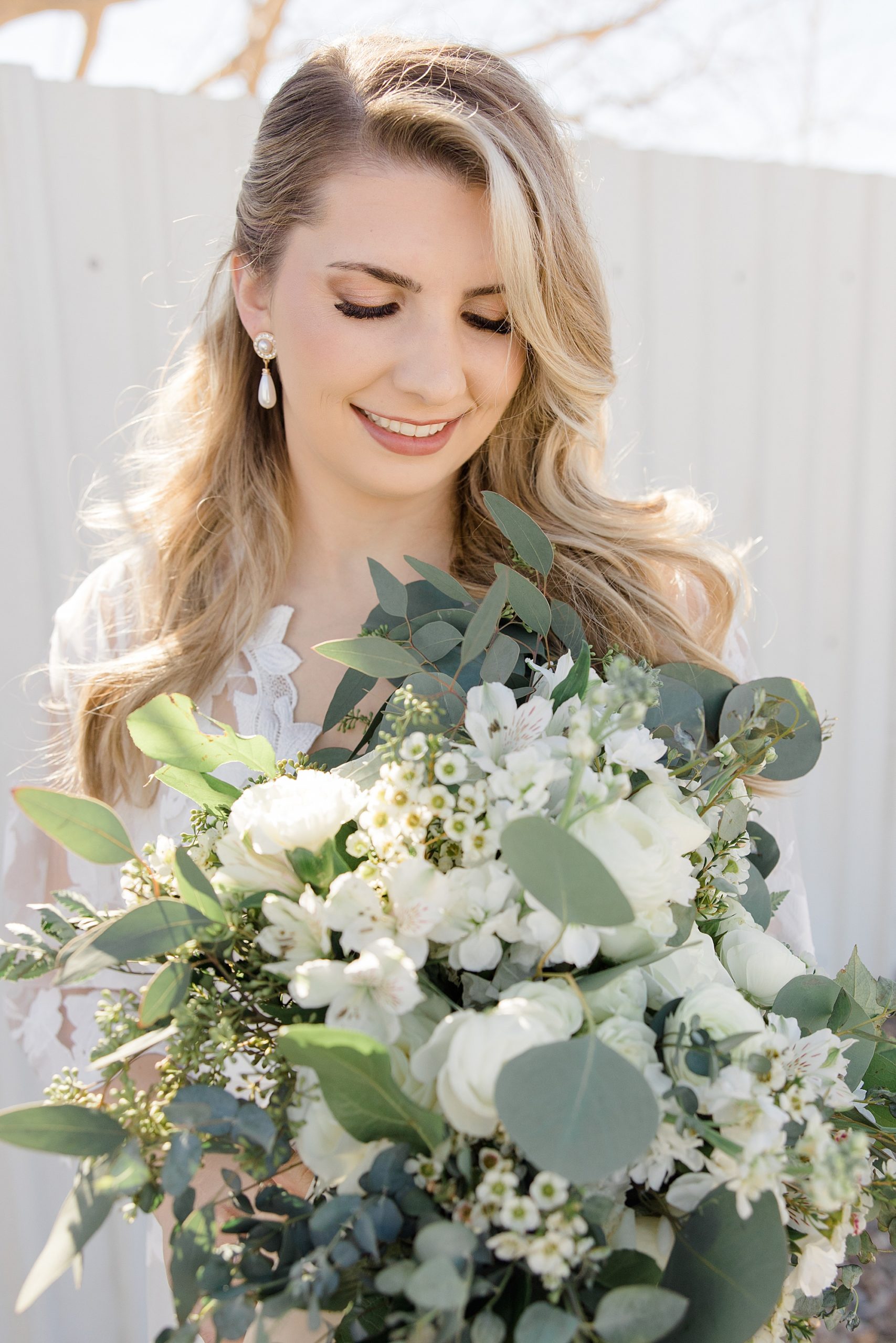 bride holds bouquet of white and green flowers in robe