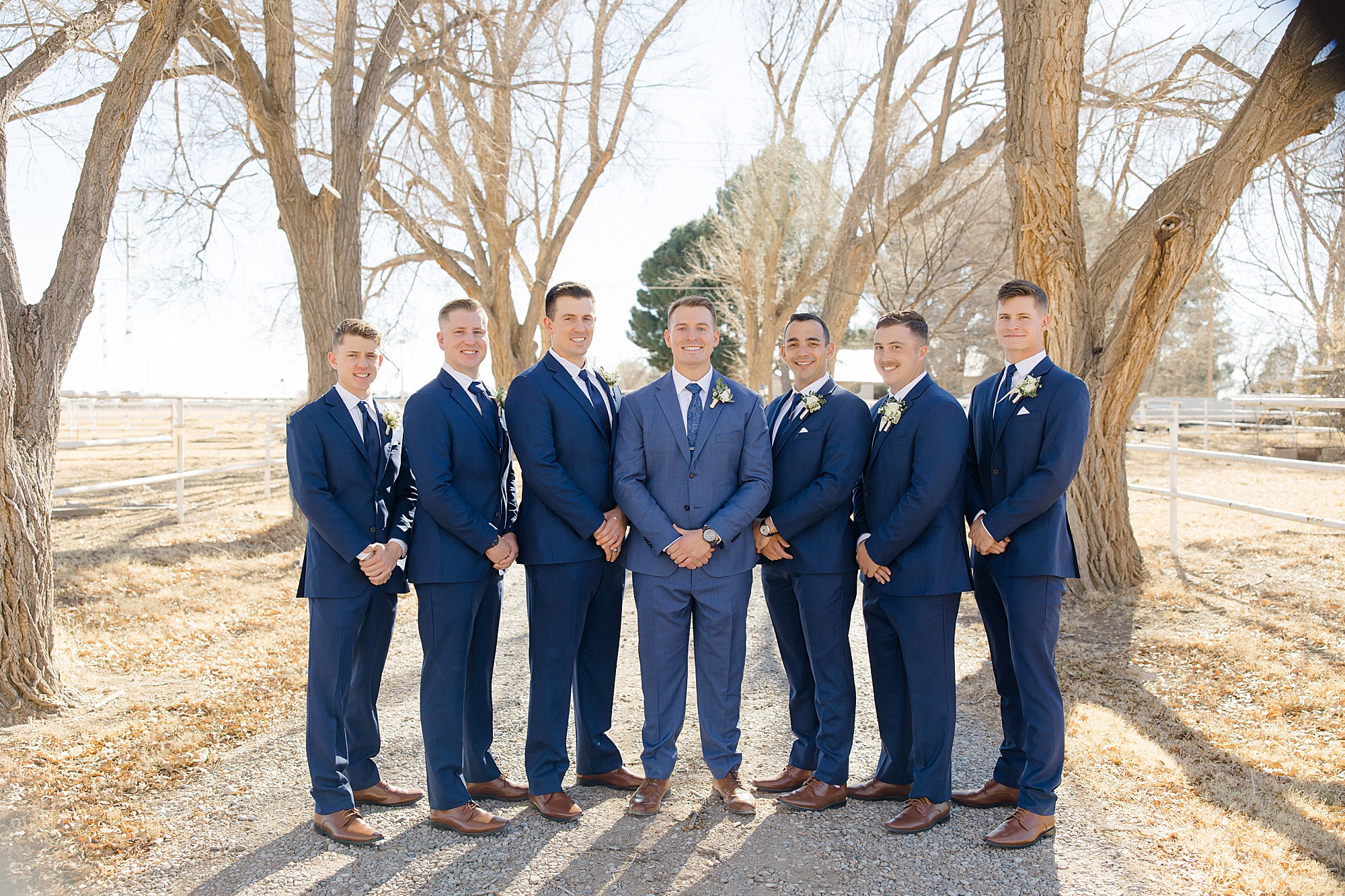 groom and groomsmen in navy suits pose together before winter wedding in Rosewell, New Mexico