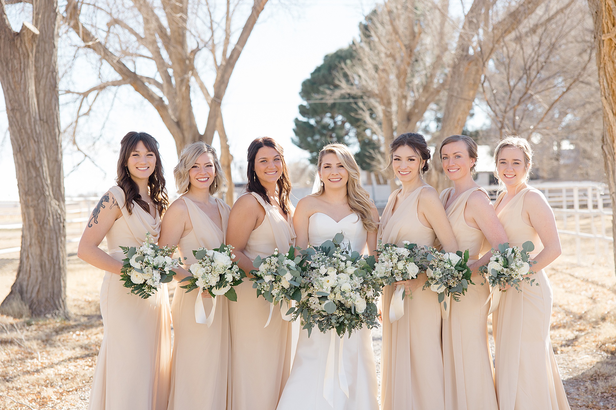 bride poses with bridesmaids in champagne gowns