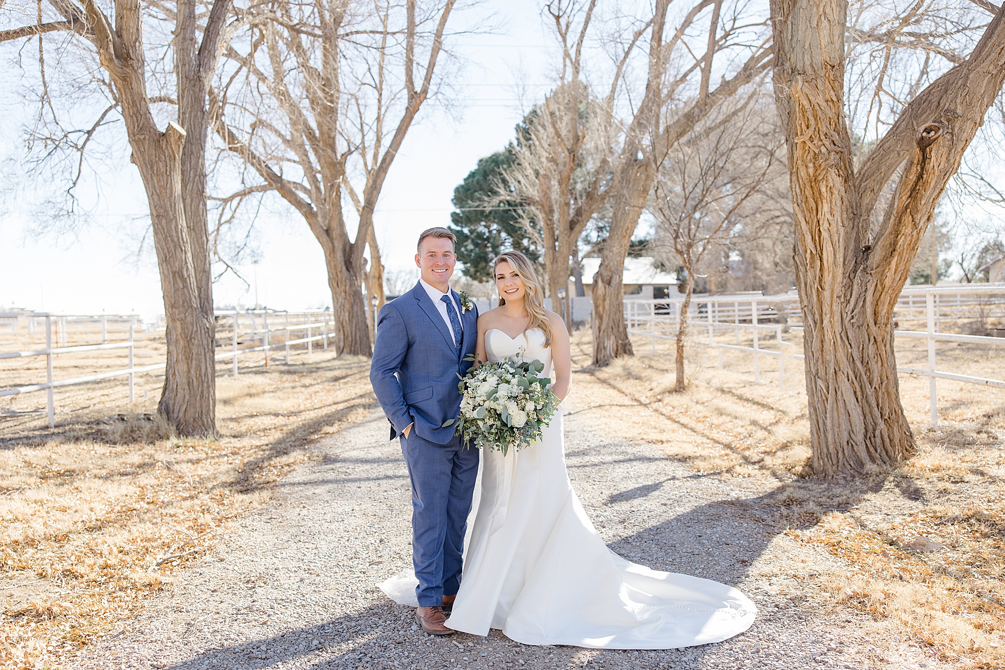 newlyweds pose on driveway during winter wedding in Rosewell, New Mexico