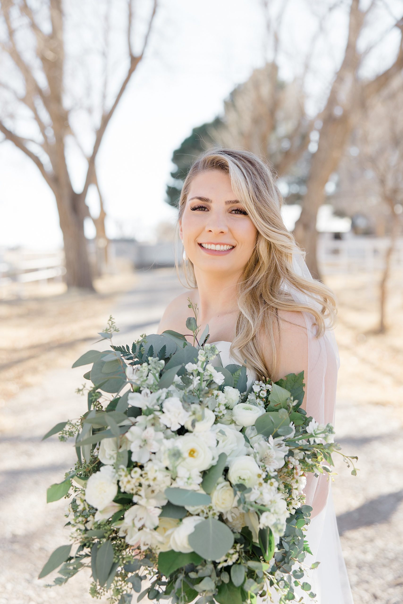 bride holds bouquet of white flowers before winter wedding