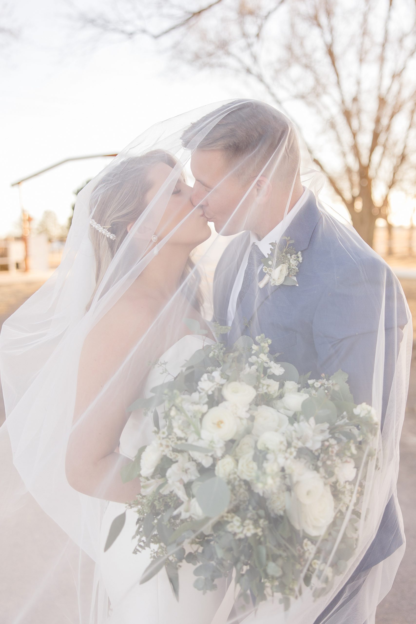 bride and groom kiss under veil during portraits