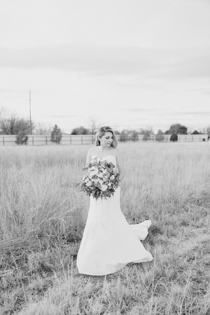 bride stands in field with winter bouquet 