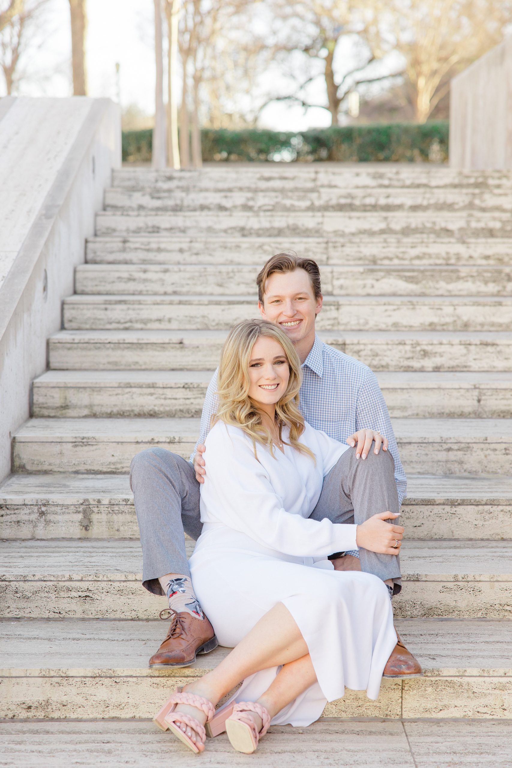 bride and groom sit on steps during Texas engagement photos 
