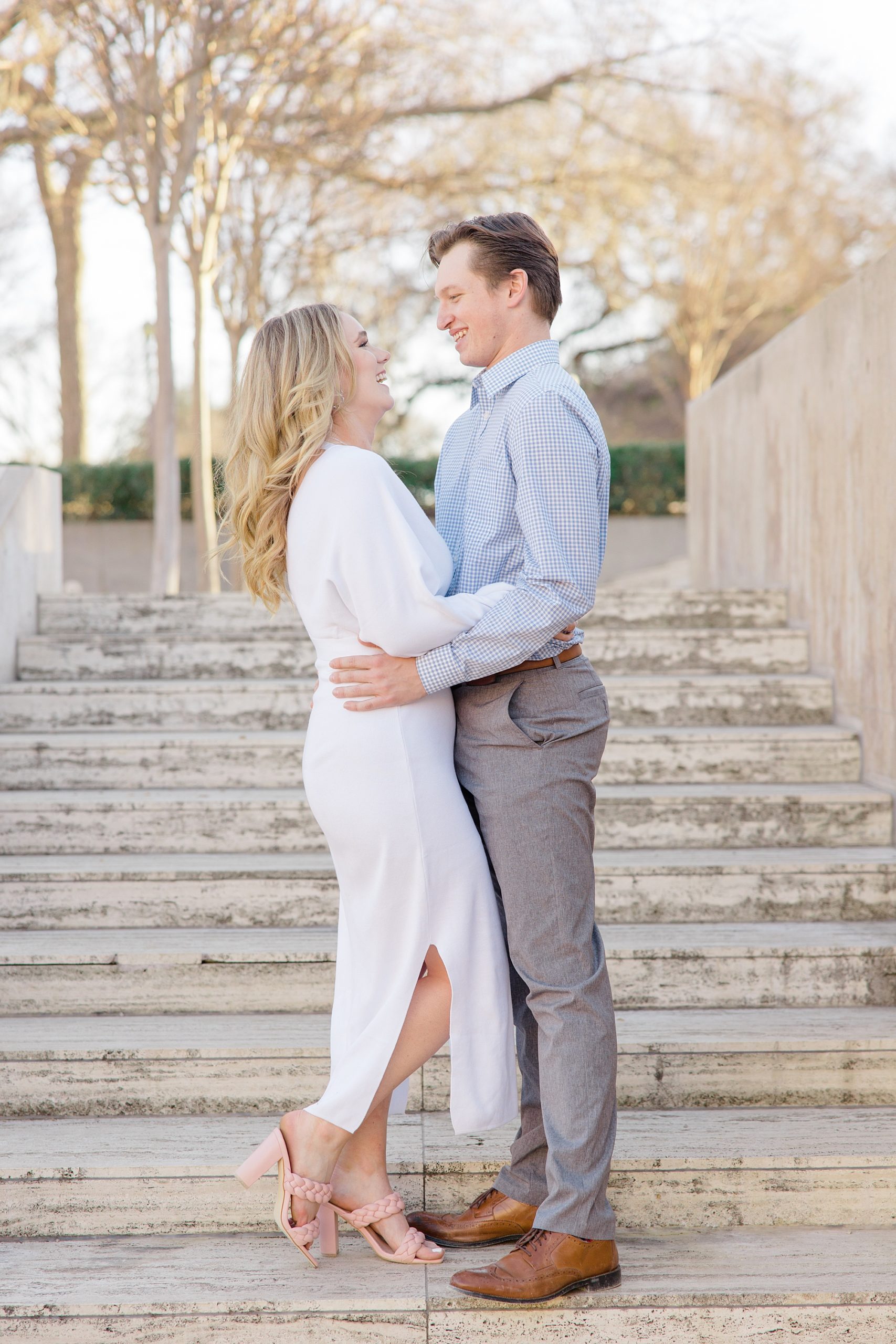 engaged couple smiles standing on steps in Kimball Art Museum 