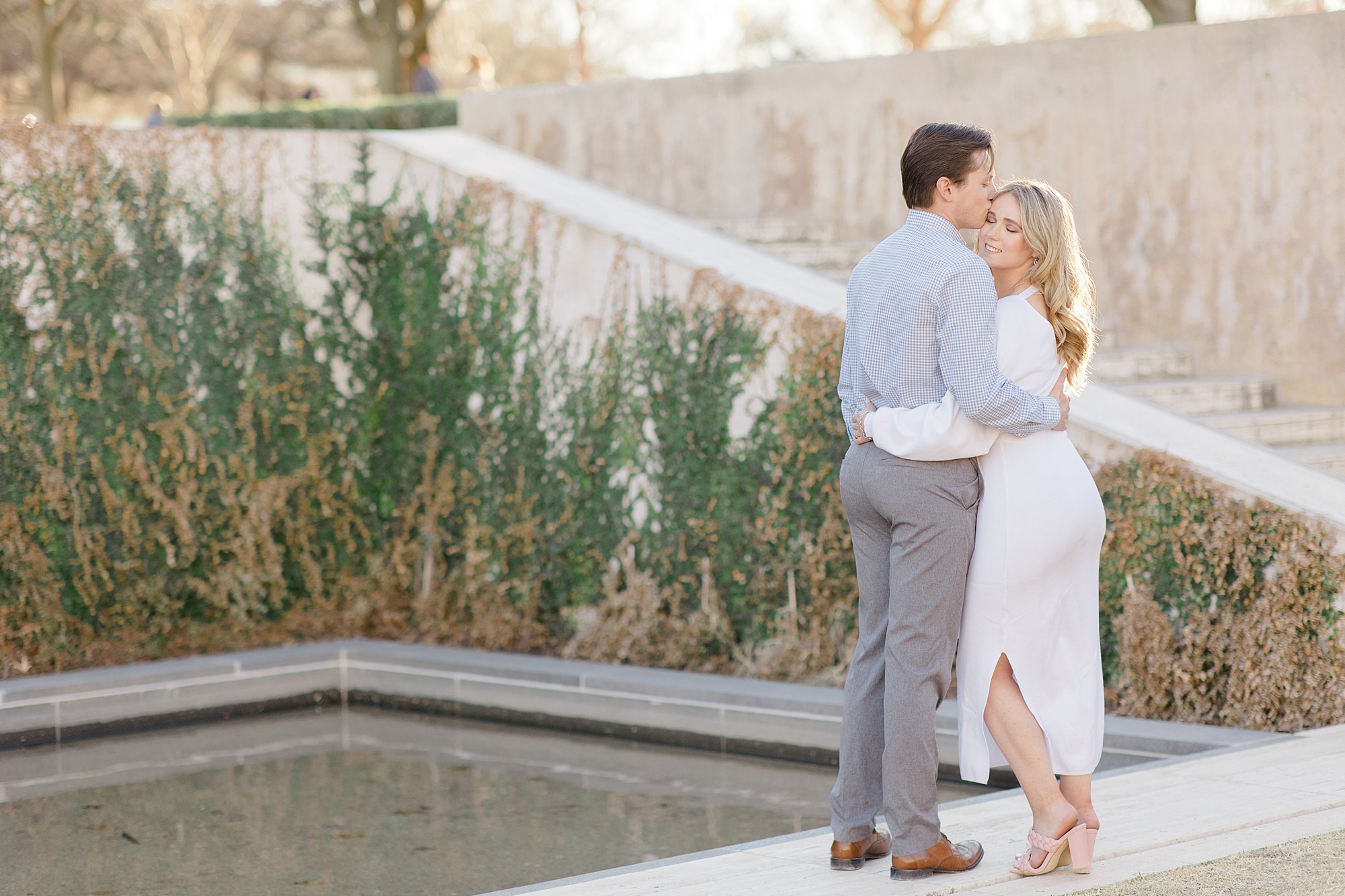 bride and groom pose by pond at Kimball Art Museum hugging 