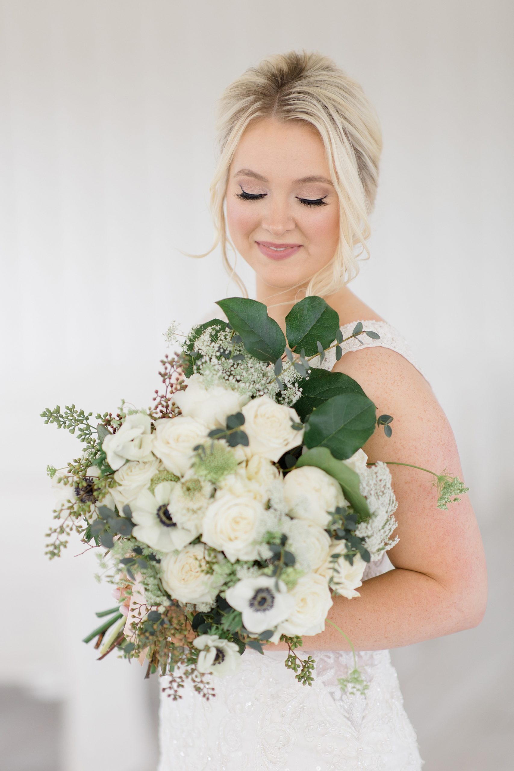 bride looks down at bouquet of white flowers during The Grand Ivory bridal session