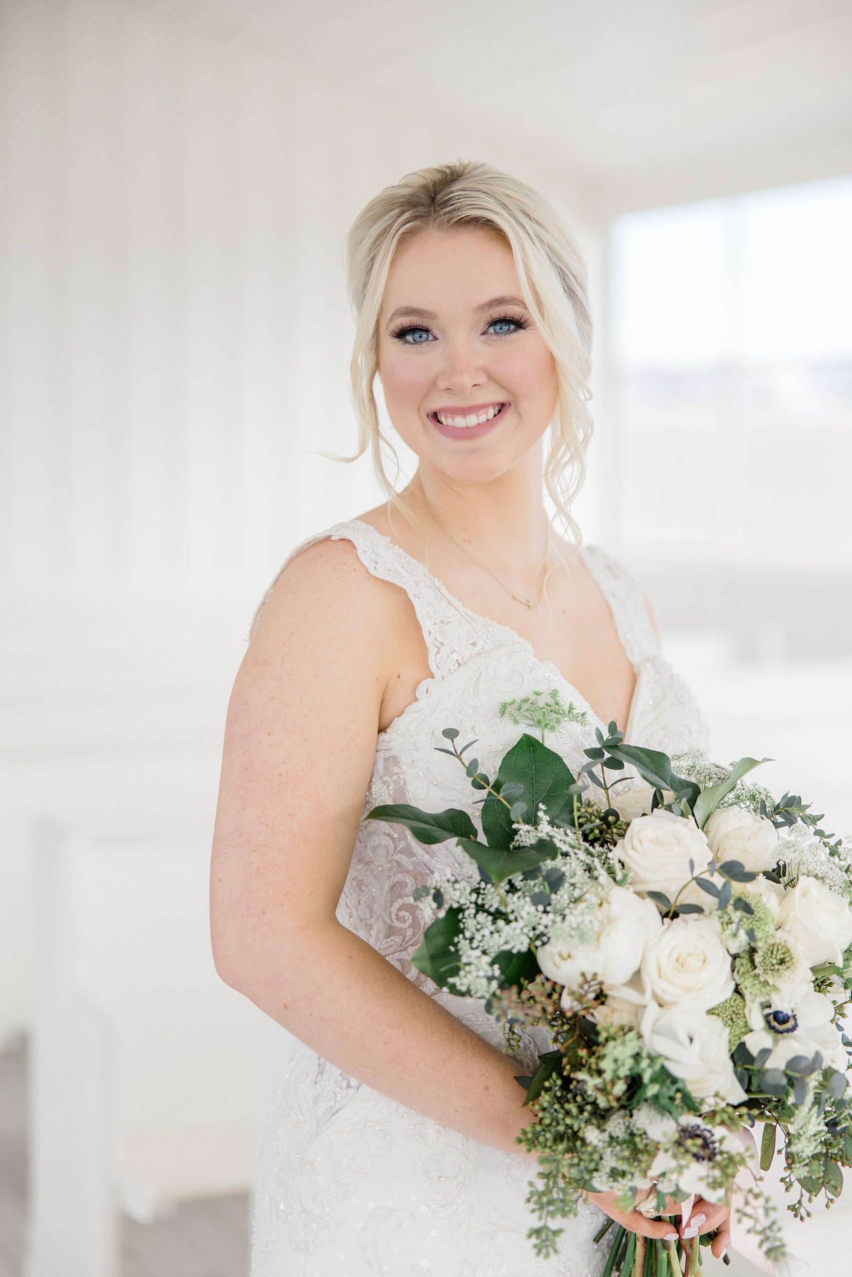 bride holds bouquet of white flowers and greenery during bridal session at The Grand Ivory