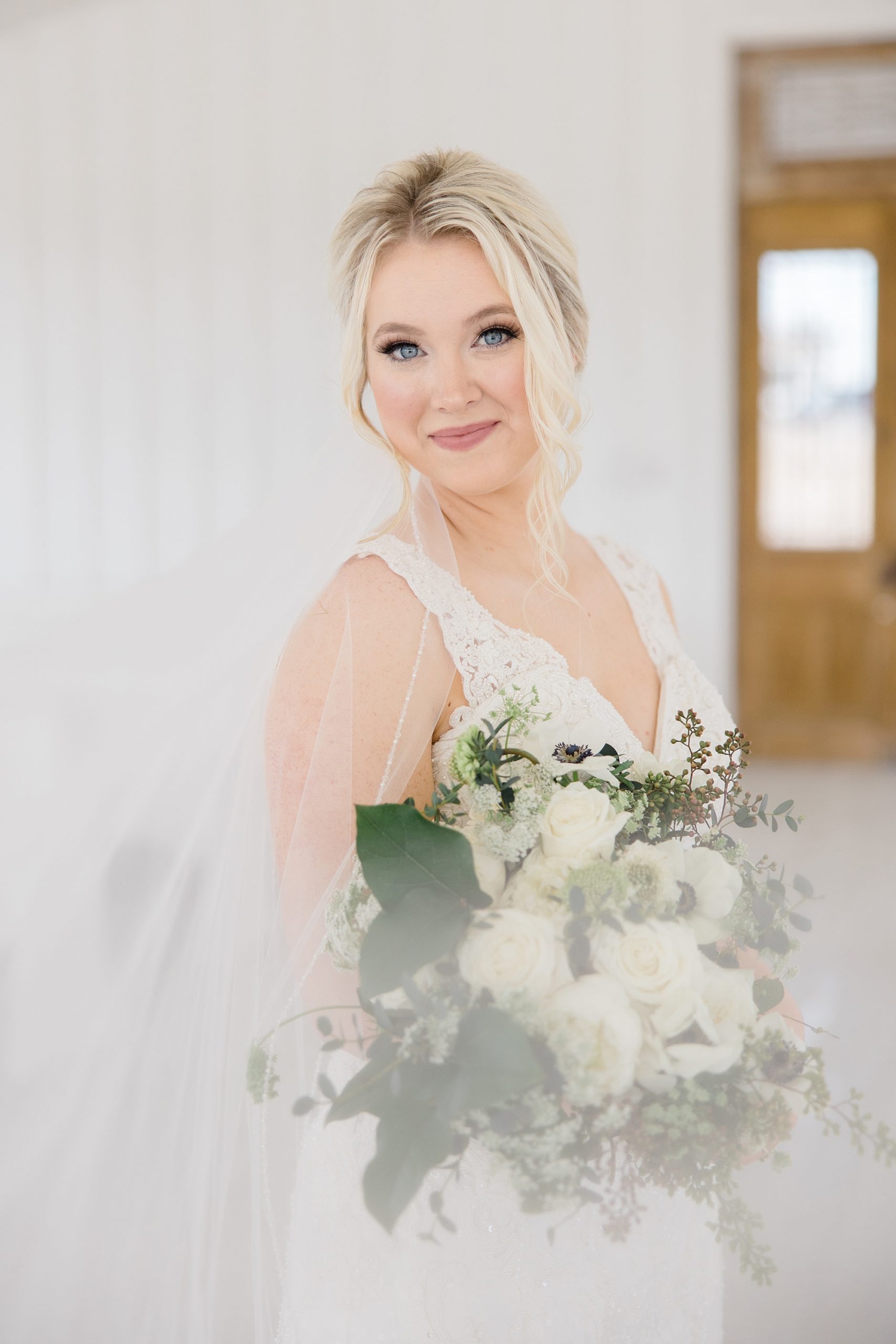 bride smiles holding her bouquet with veil draped around her