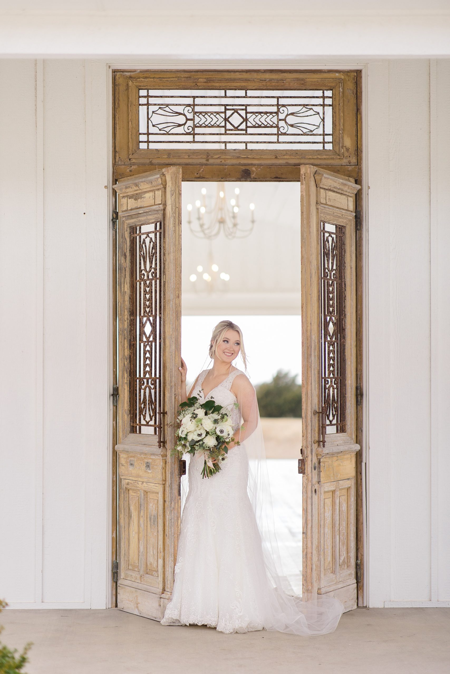 bride poses in wooden doors at the The Grand Ivory chapel
